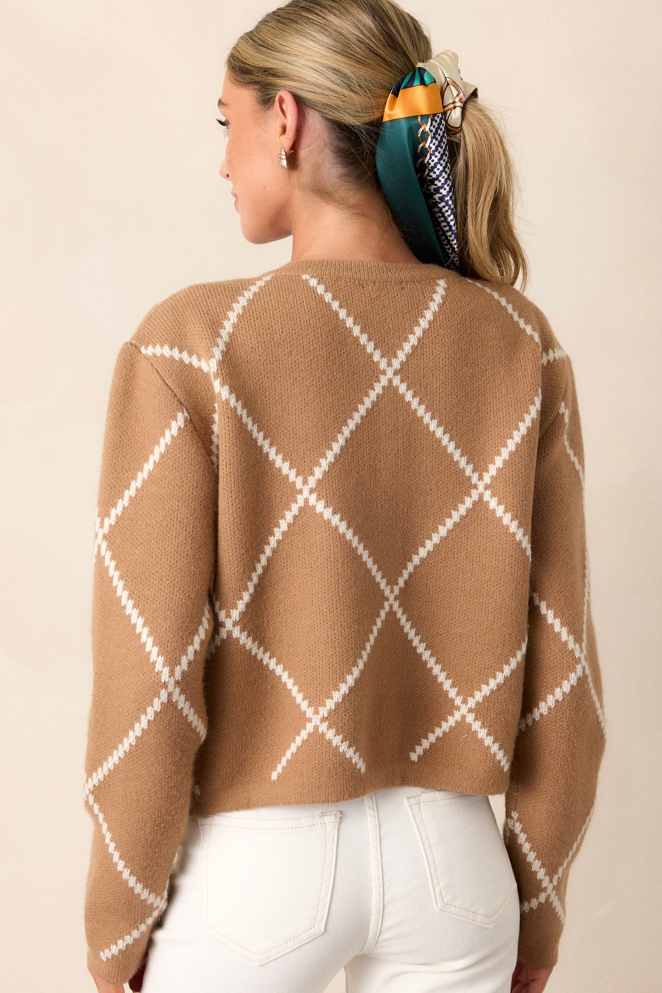 A view of the back of the sweater, highlighting the continuation of the tan and white knit argyle pattern and the smooth, tailored fit across the shoulders.