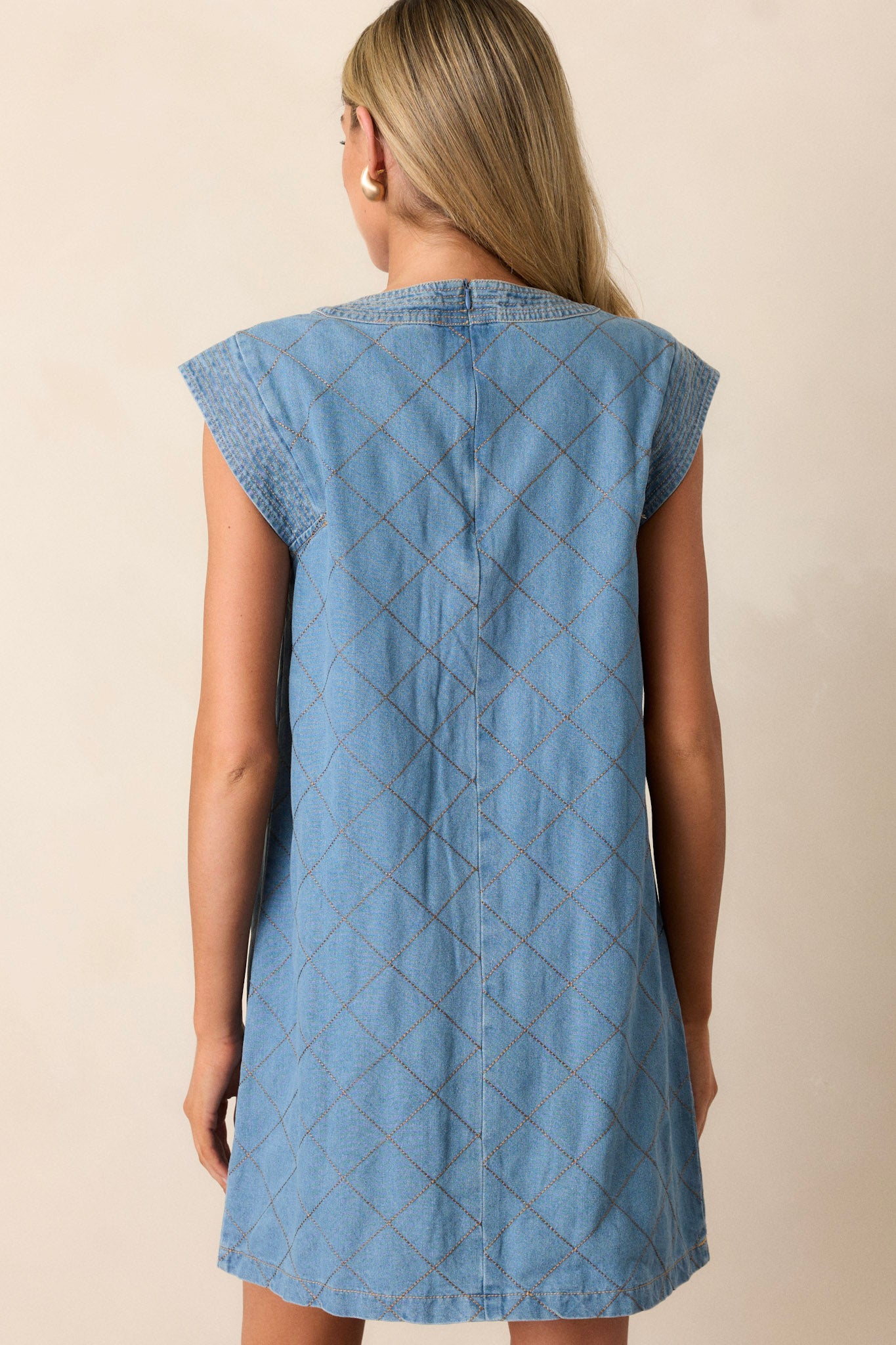 Back view of a quilted mini dress highlighting the hidden back zipper and overall fit.