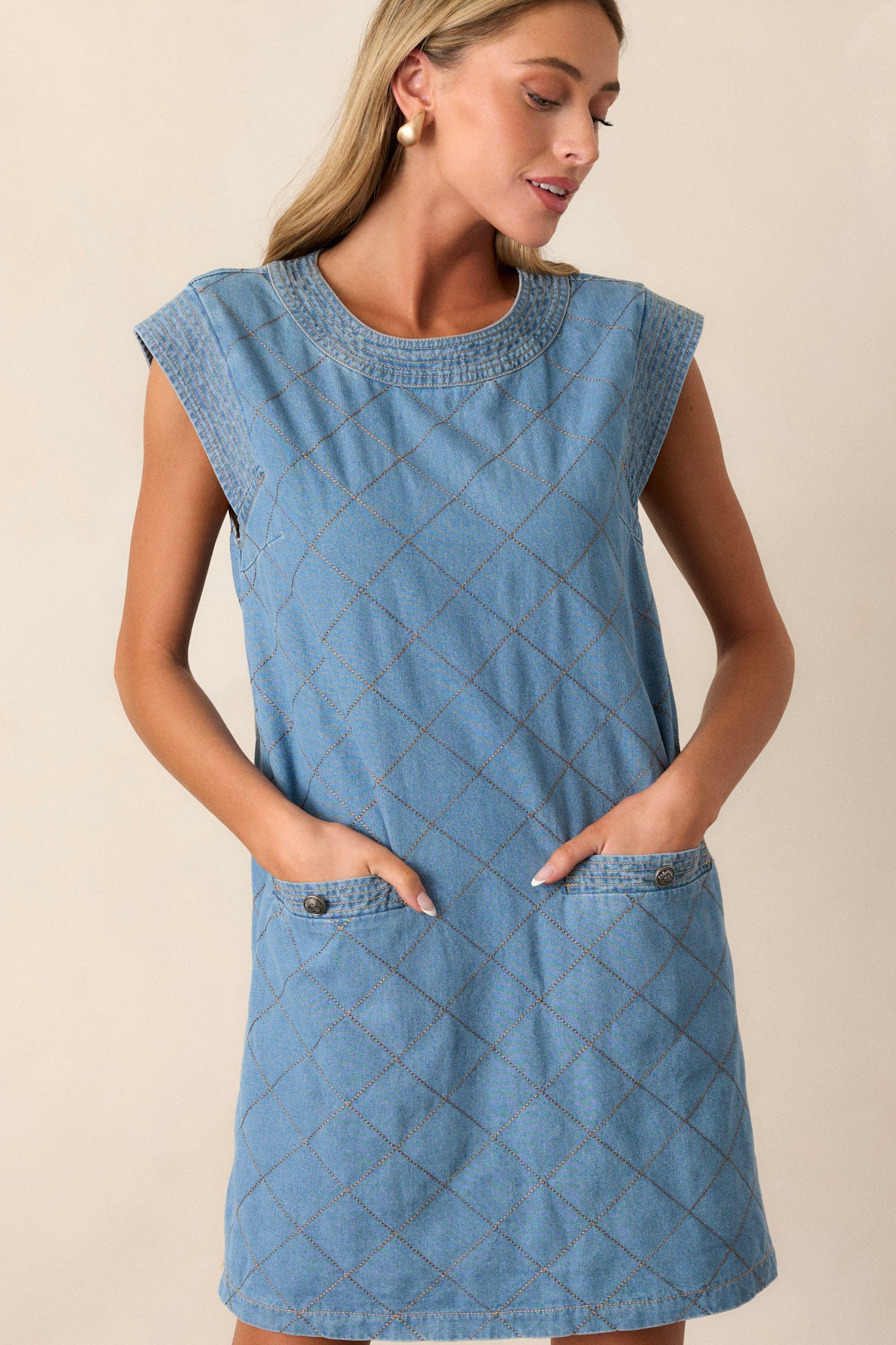 This quilted mini dress features a round neckline, cognac quilted design, a hidden back zipper, and functional pockets