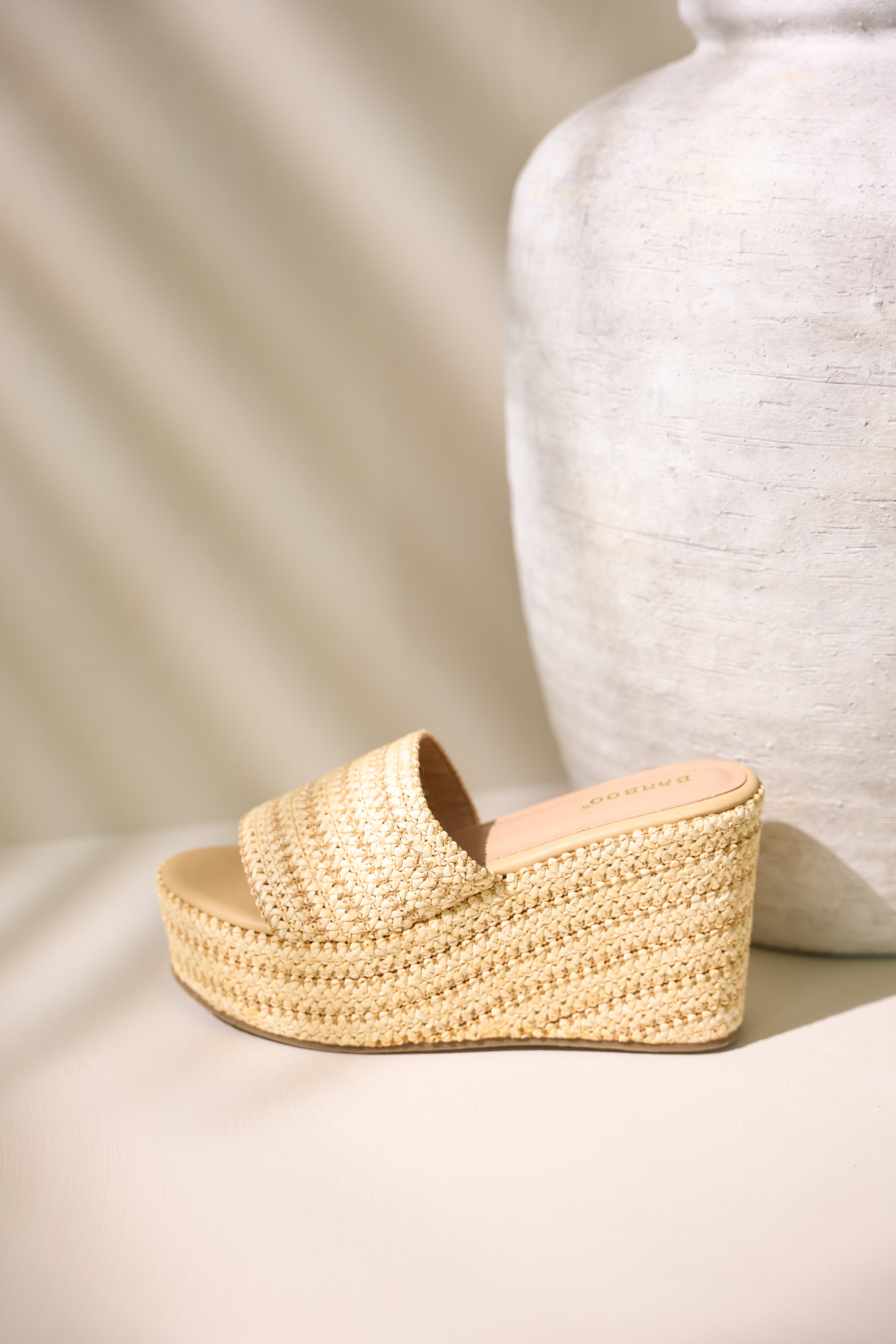 Side view of natural sandals showcasing the slide on style, raffia material, and platform design.