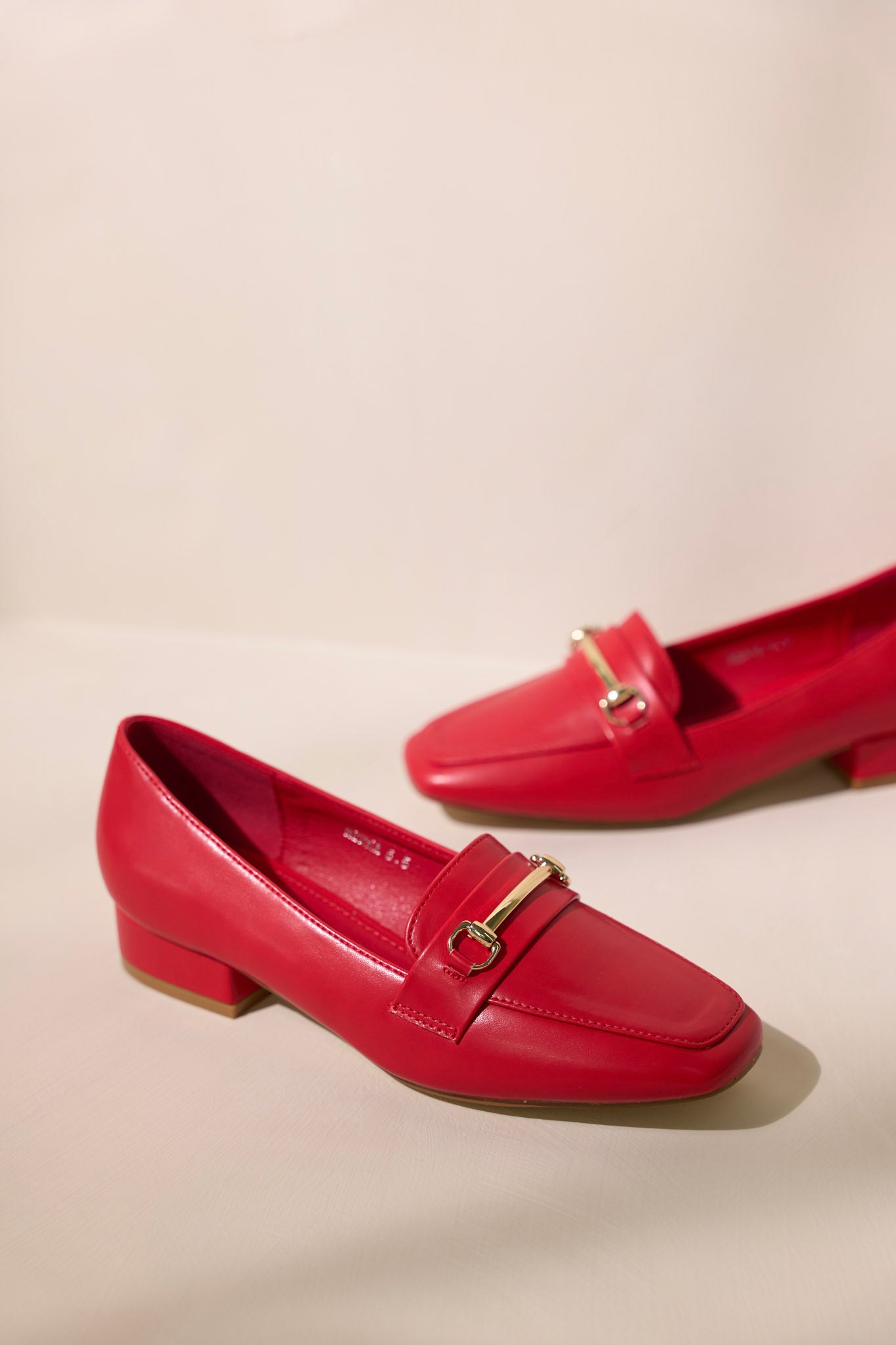 These red loafers feature a slip on design, a small heel, a square toe, and gold hardware.