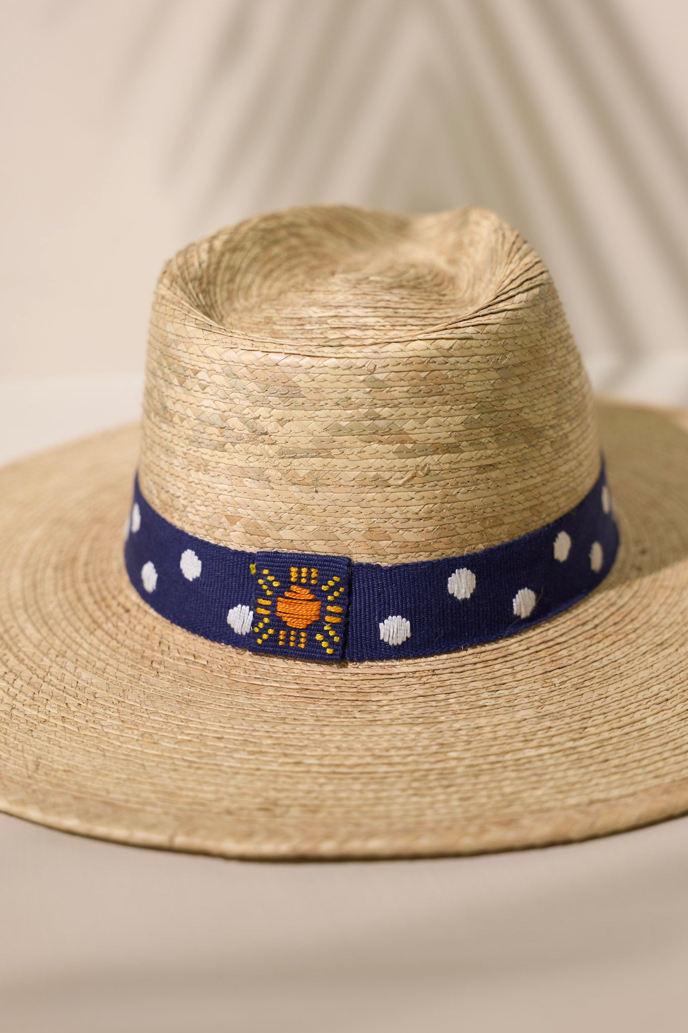 Close up view of this Wendy hat features a navy, cotton woven band with white polka dots.