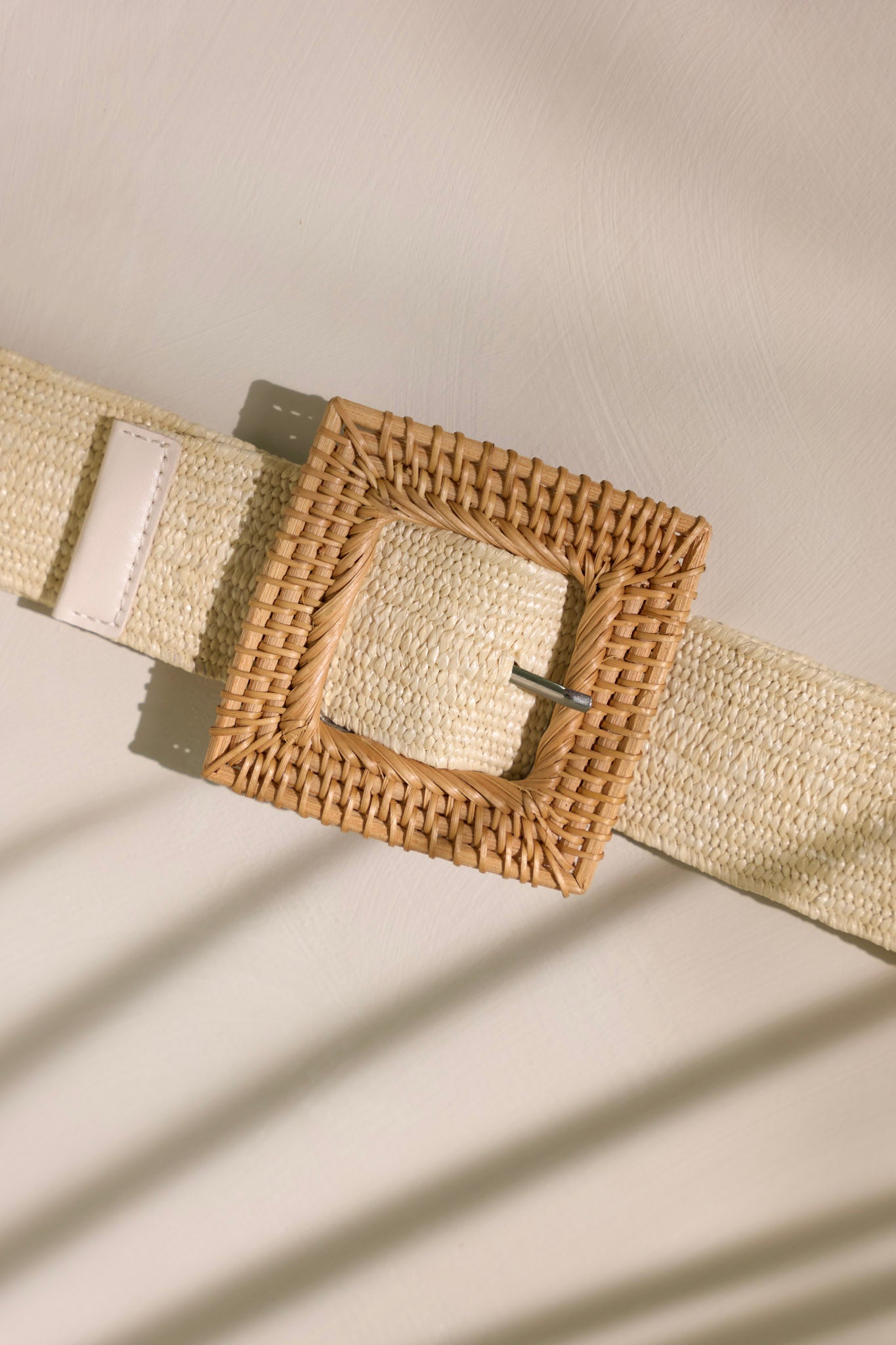 This belt features a square belt buckle and a woven material.