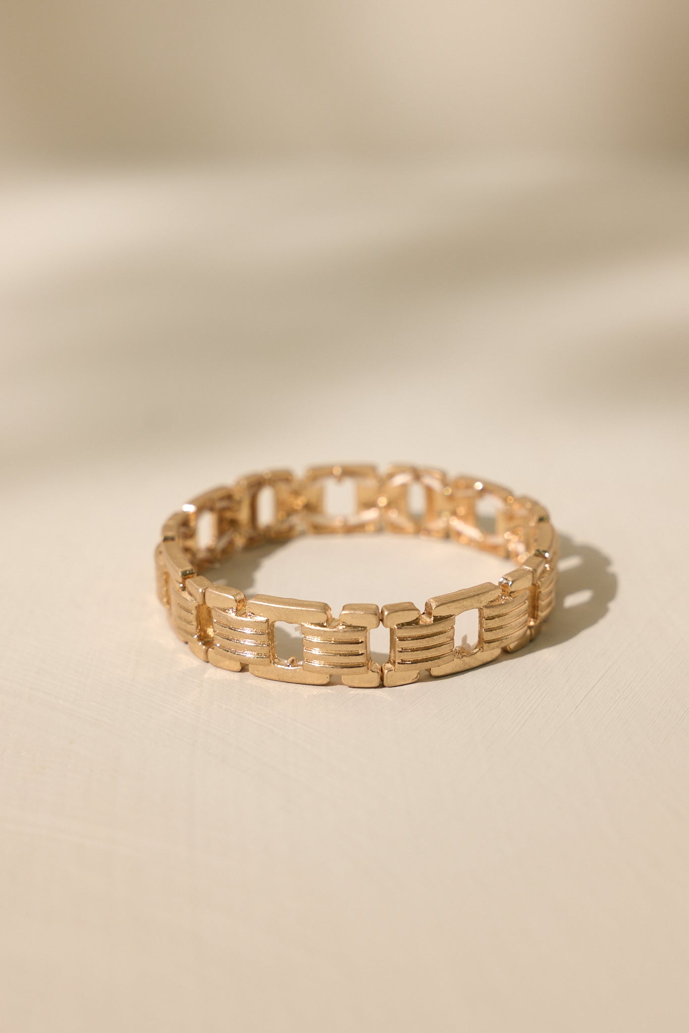 Stand alone of this gold bracelet featuring a worn gold finish, a chain-like design, and elastic bands underneath.