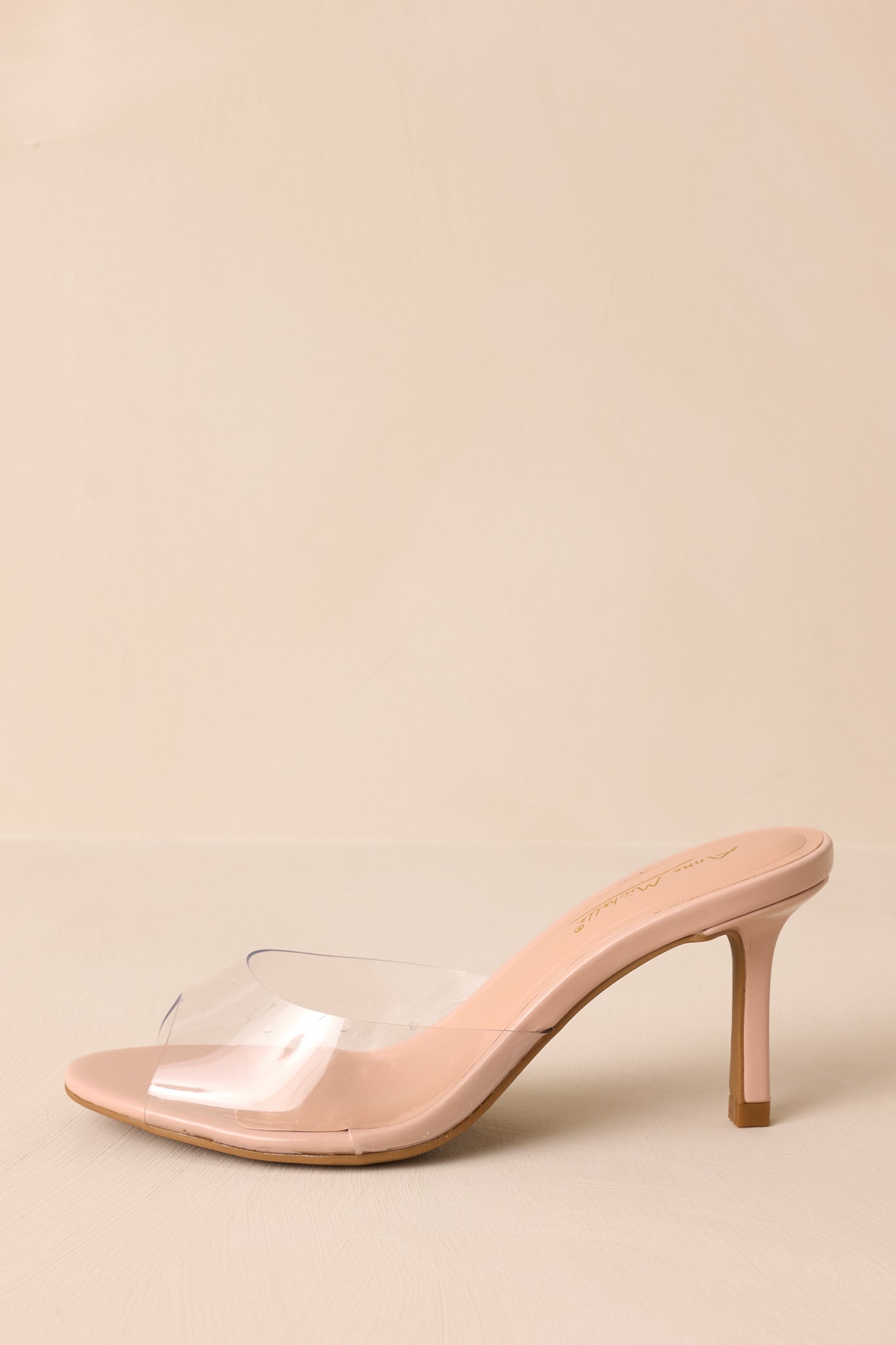 Side view of these nude heels that feature a rounded toe, a clear thick toe strap and extra heel cushioning.