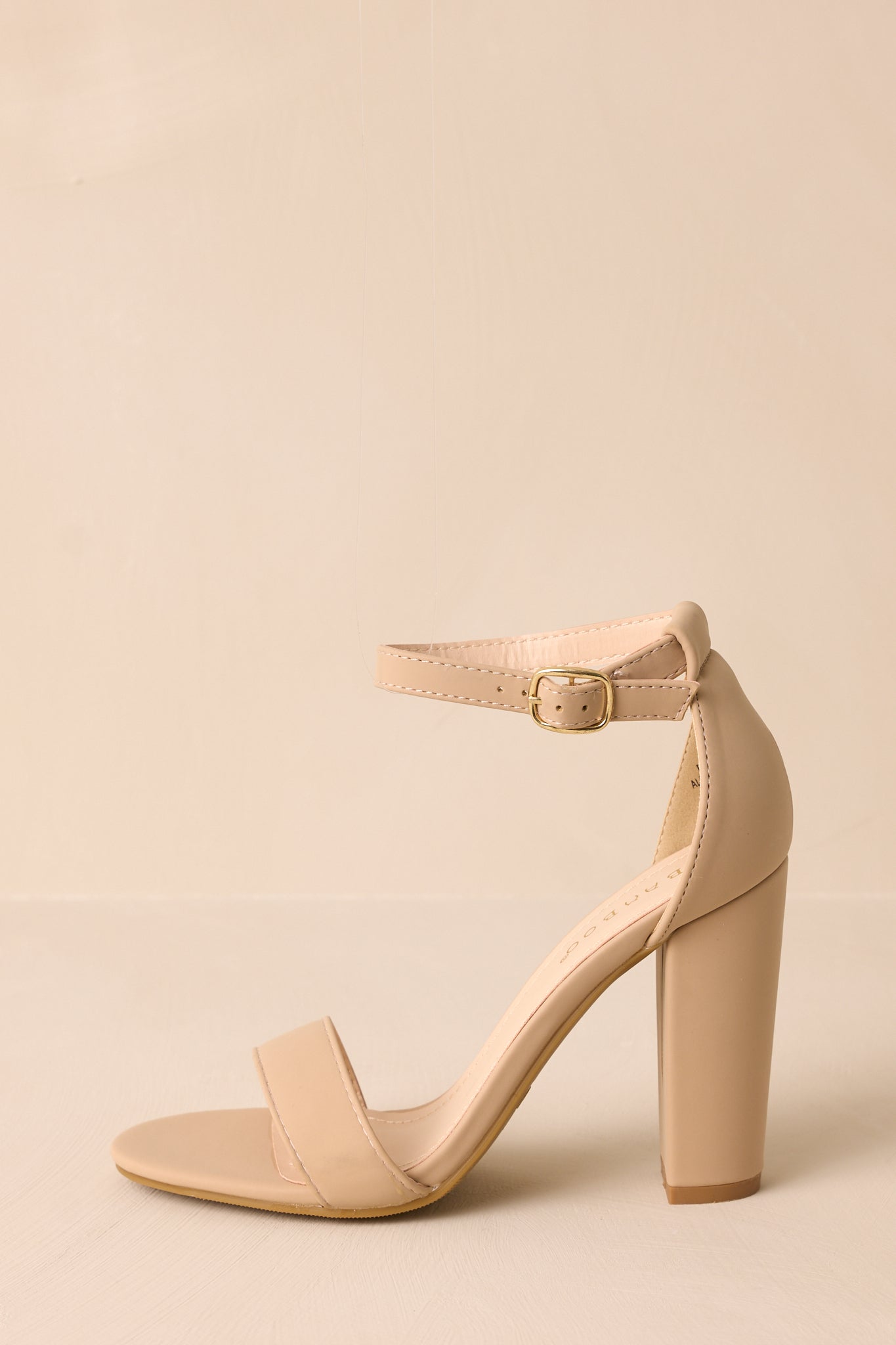 Taupe heels featuring a sleek design with an adjustable ankle strap, a wide toe strap, and a sturdy thick block heel.