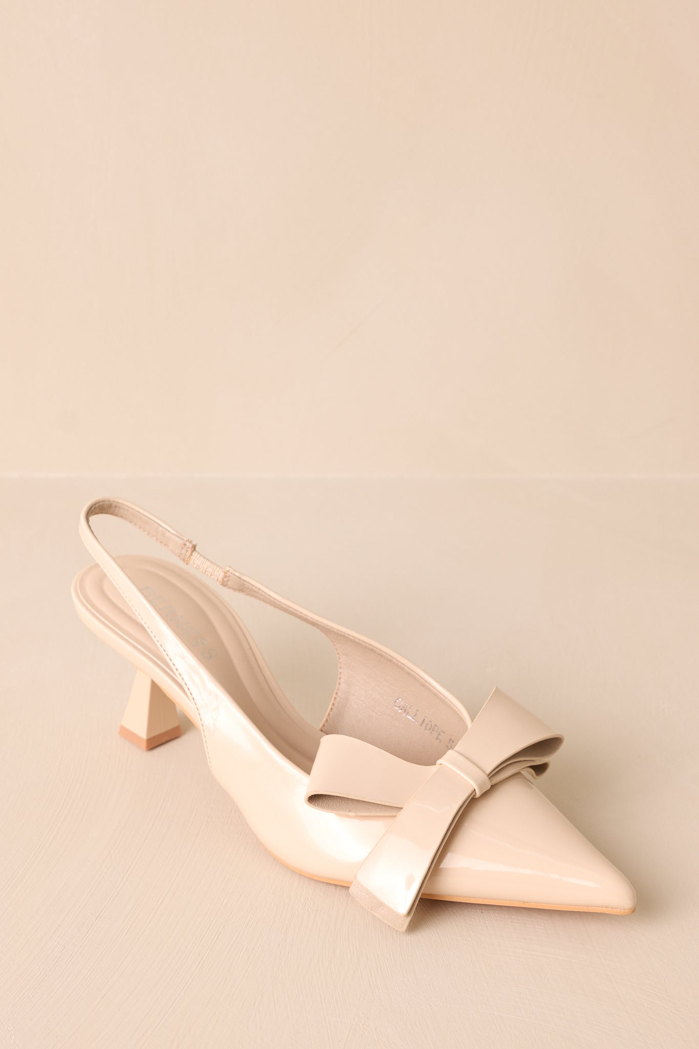 A cropped view of the ivory heels showcasing the pointed toe design and the elegant bow detail at the front, highlighting their stylish appeal.