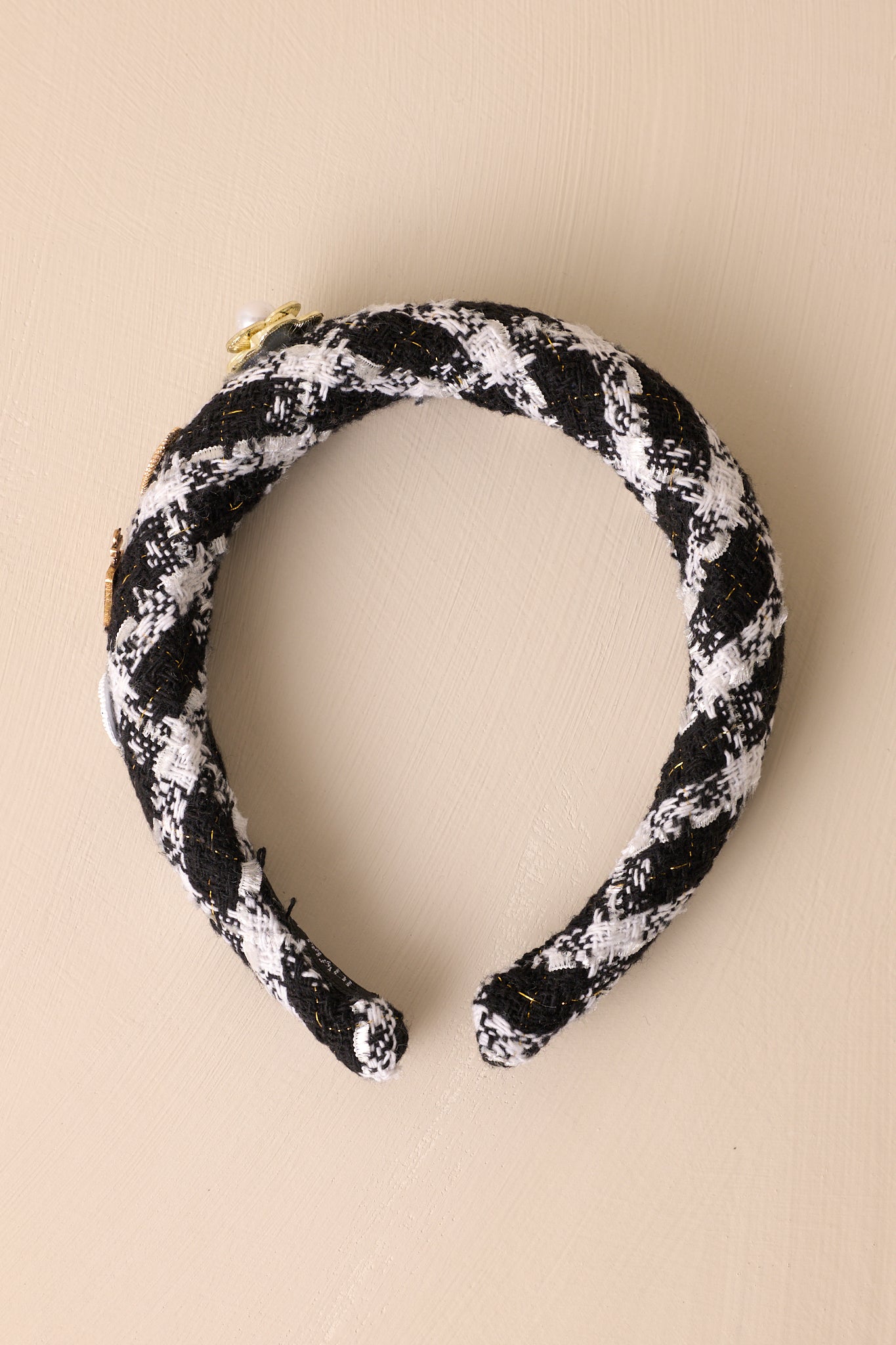 Over-head view of this headband that features a black and white tweed fabric, adorned with four adorable charms along one side.