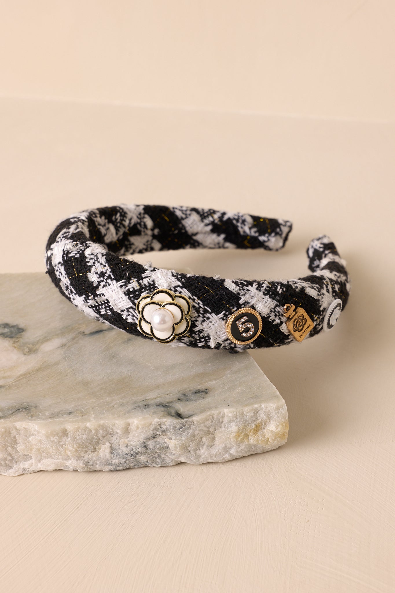 Close-up view of this headband that features a black and white tweed fabric, adorned with four adorable charms along one side.