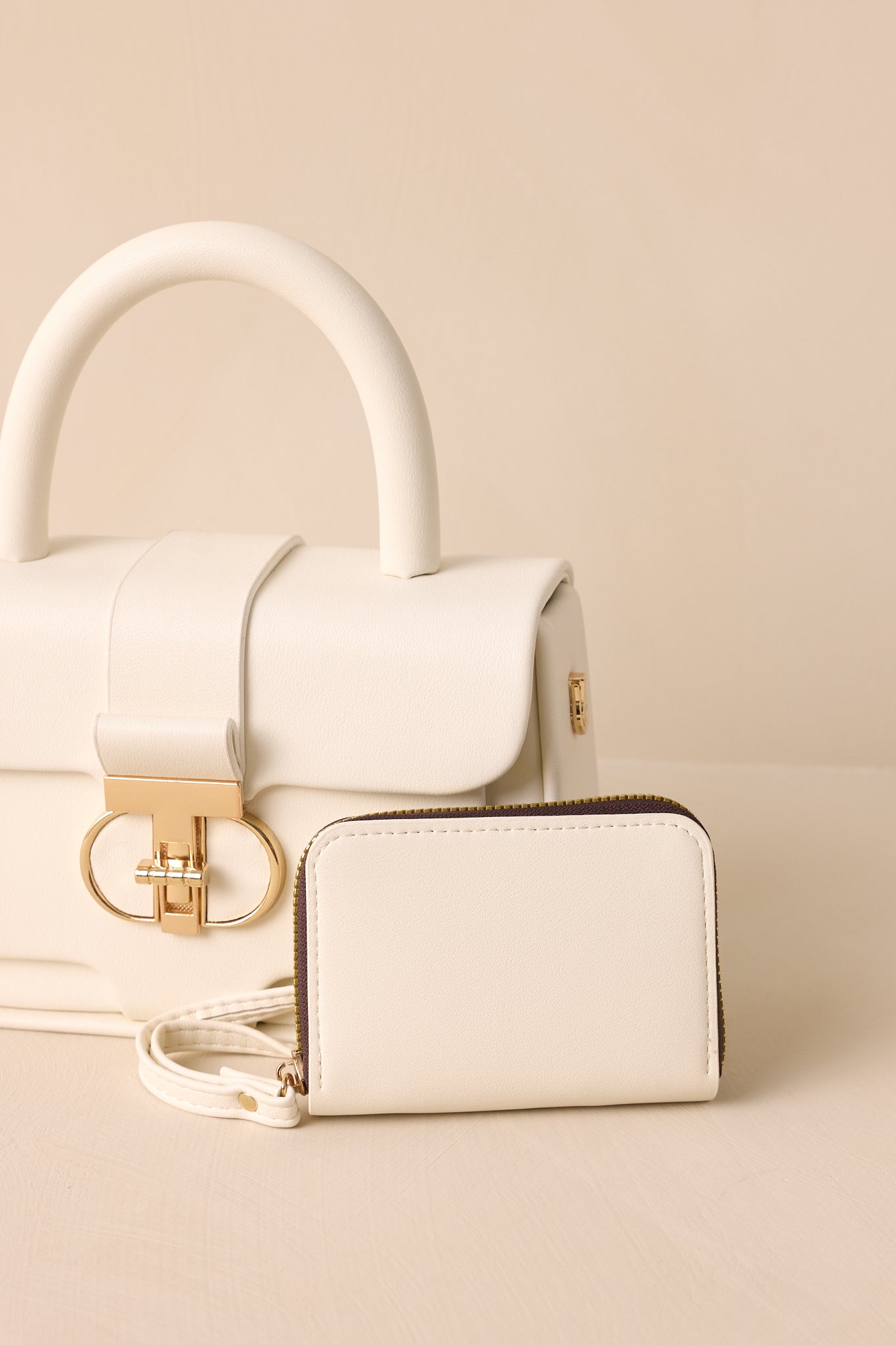 A detailed look at the white handbag’s top handle, highlighting the gold hardware and a glimpse of the included inside wallet.