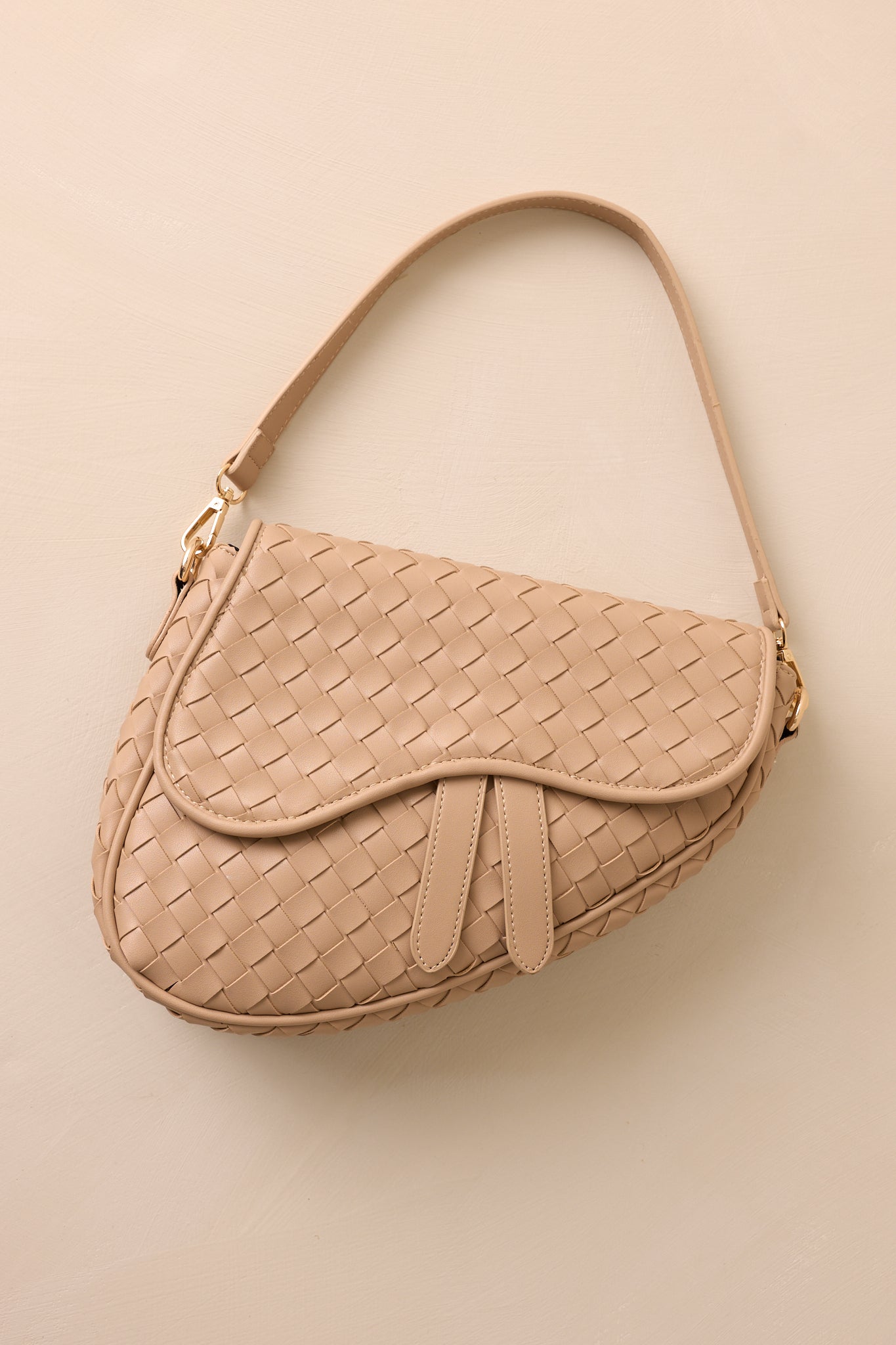 This beige handbag features gold hardware, faux leather, a woven design, a magnetic snap closure, a zipper pocket, and an additional strap.