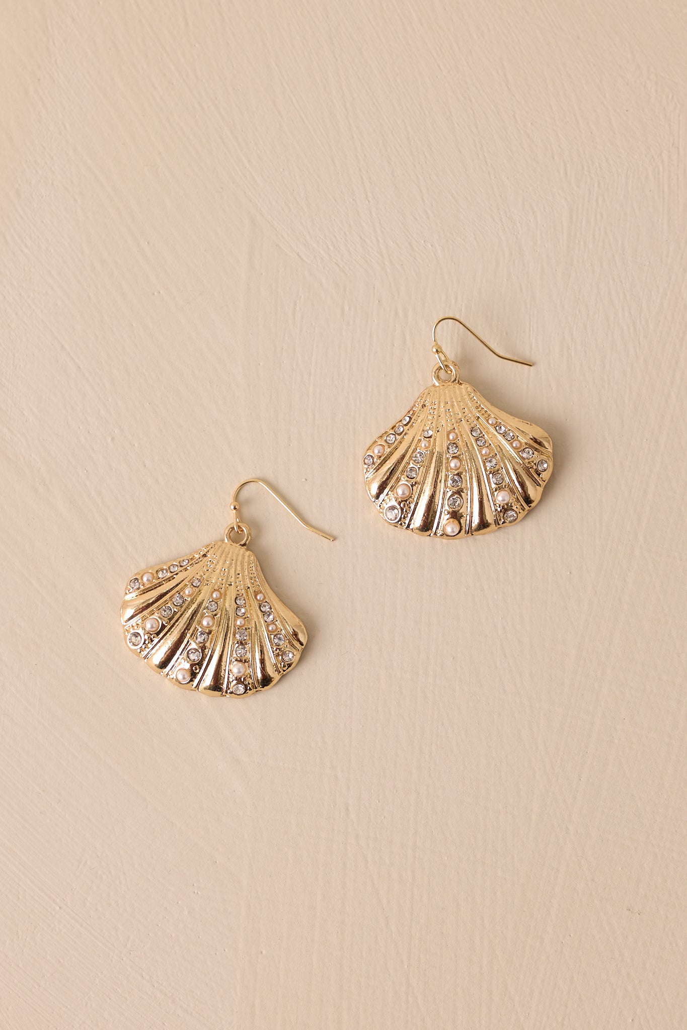 A detailed close-up of the gold earrings, showcasing the gold seashell pendant. The rhinestones sparkle against the gold, and the faux pearls add a touch of sophistication to the design.