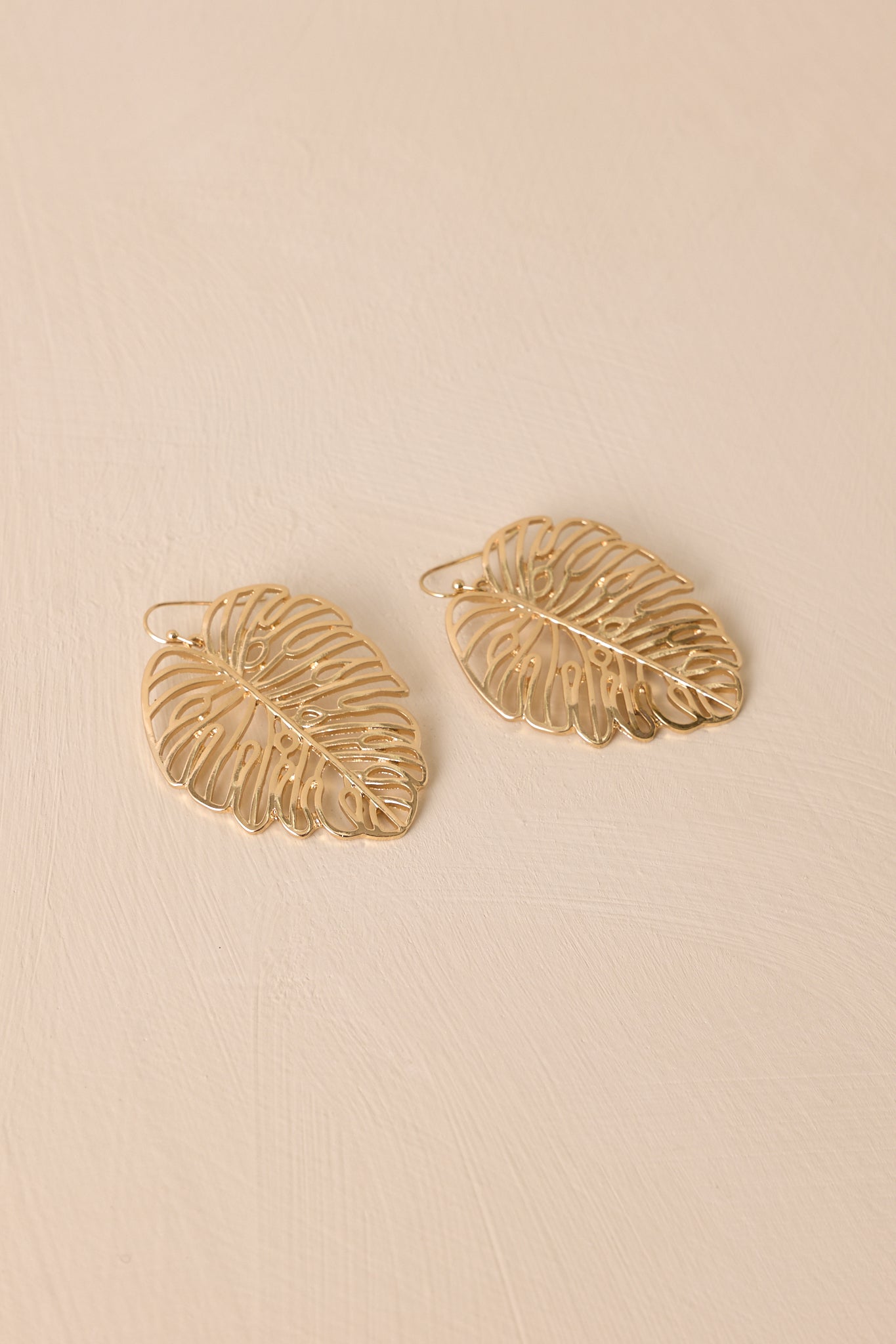 Angled view of the gold earrings, showcasing the transparent monstera leaf dangles and delicate gold hardware, perfect for adding a radiant glow to any outfit.