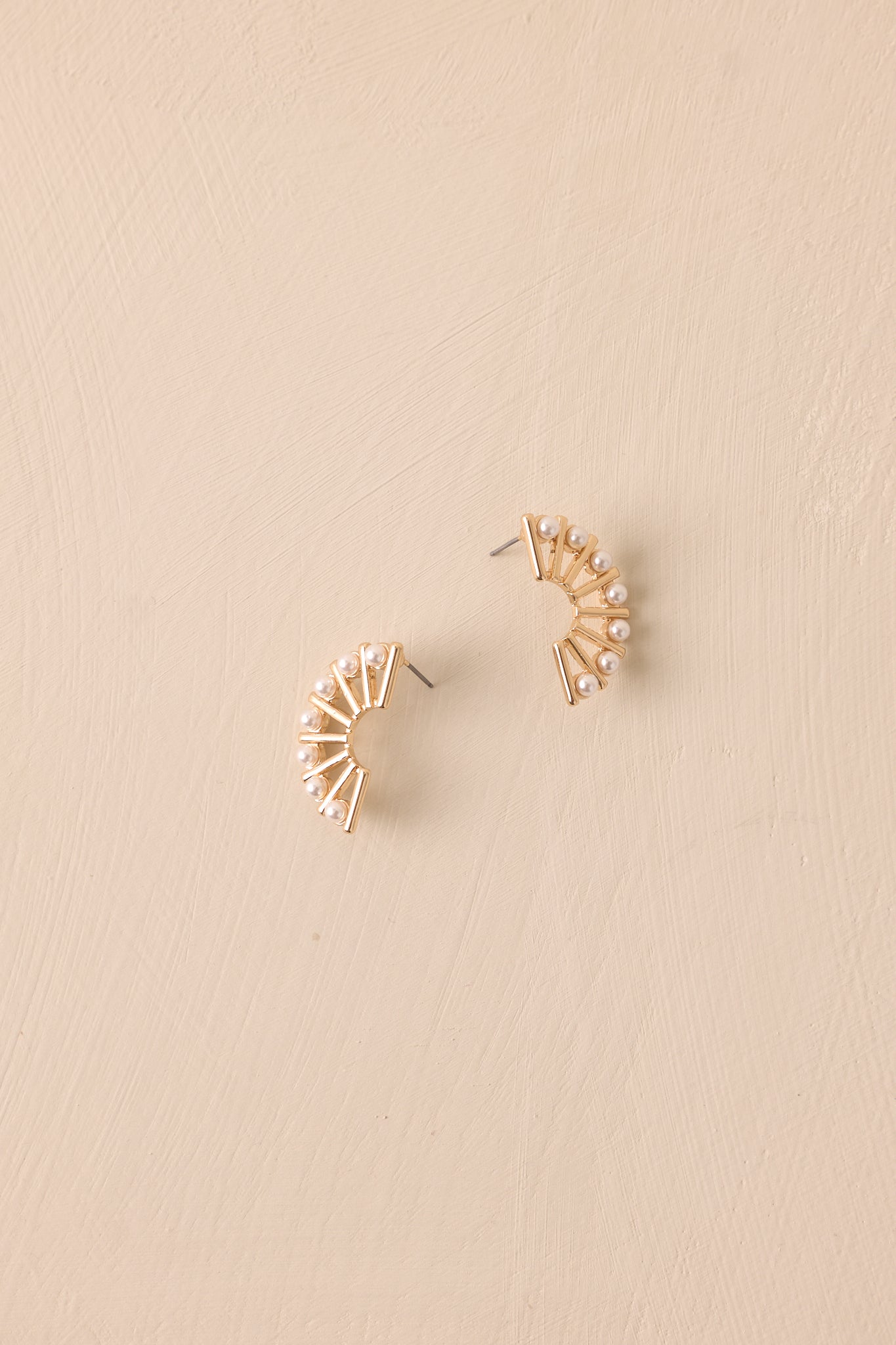 A detailed view of the gold and ivory earrings, showcasing the semi-circle shape with the indented middle and fan-like design.