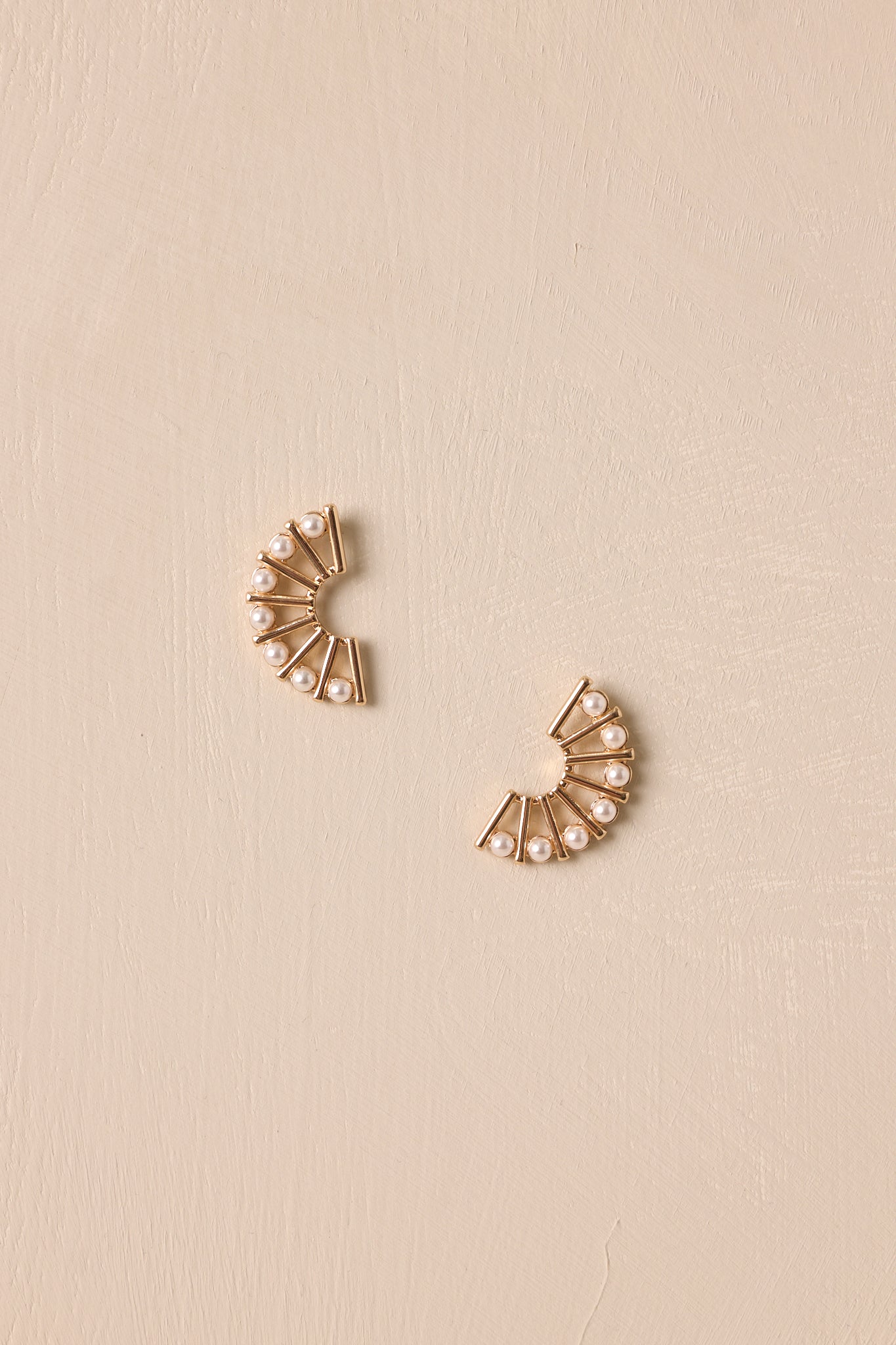 A close-up of the fan-shaped edges, highlighting the small ivory faux pearls adorning the ends of the gold hardware.