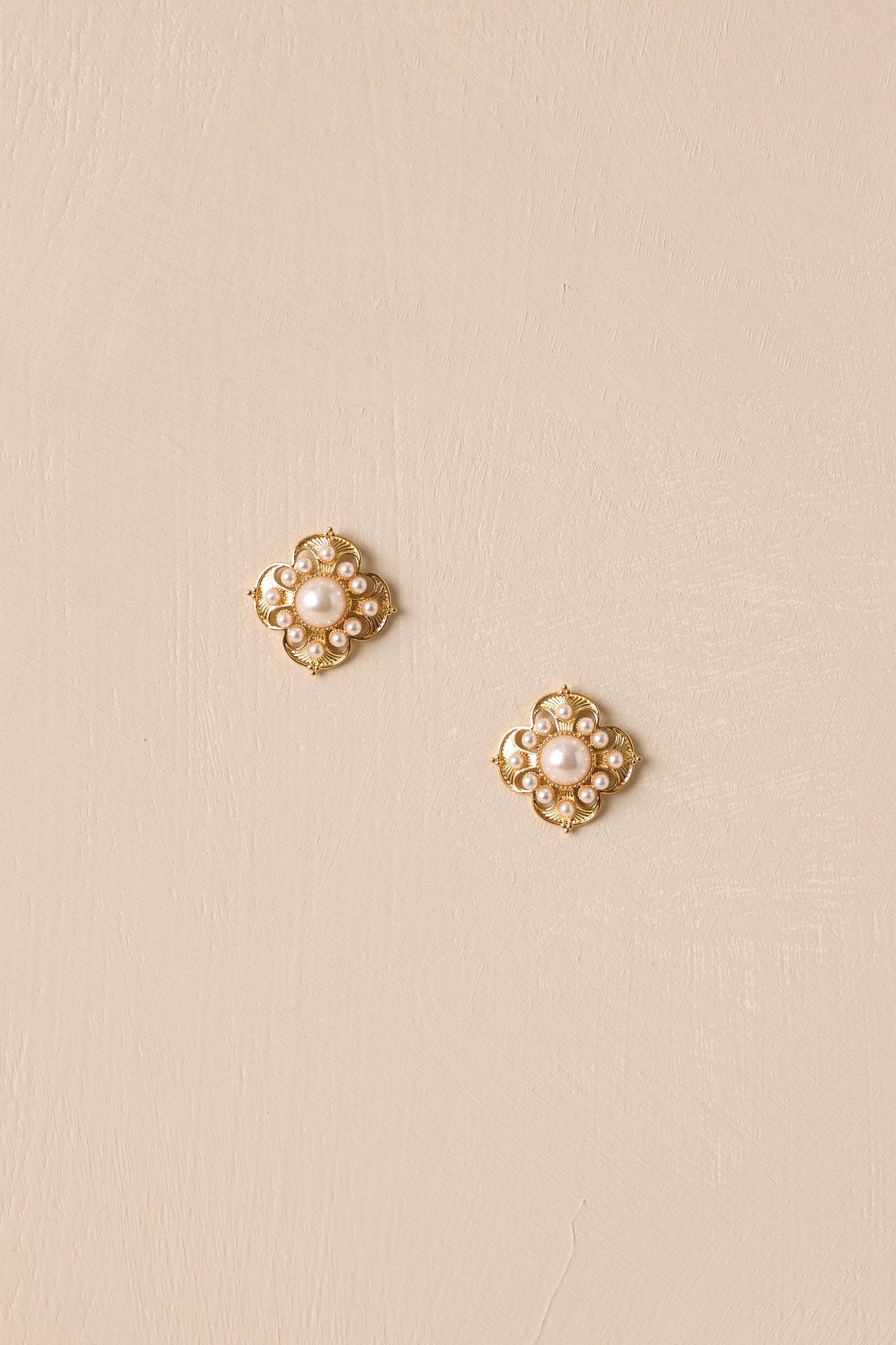 Front view of the gold and ivory earrings, showcasing the floral-shaped body and the medium-sized ivory faux pearl at the center, surrounded by mini faux pearls that add a delicate touch.