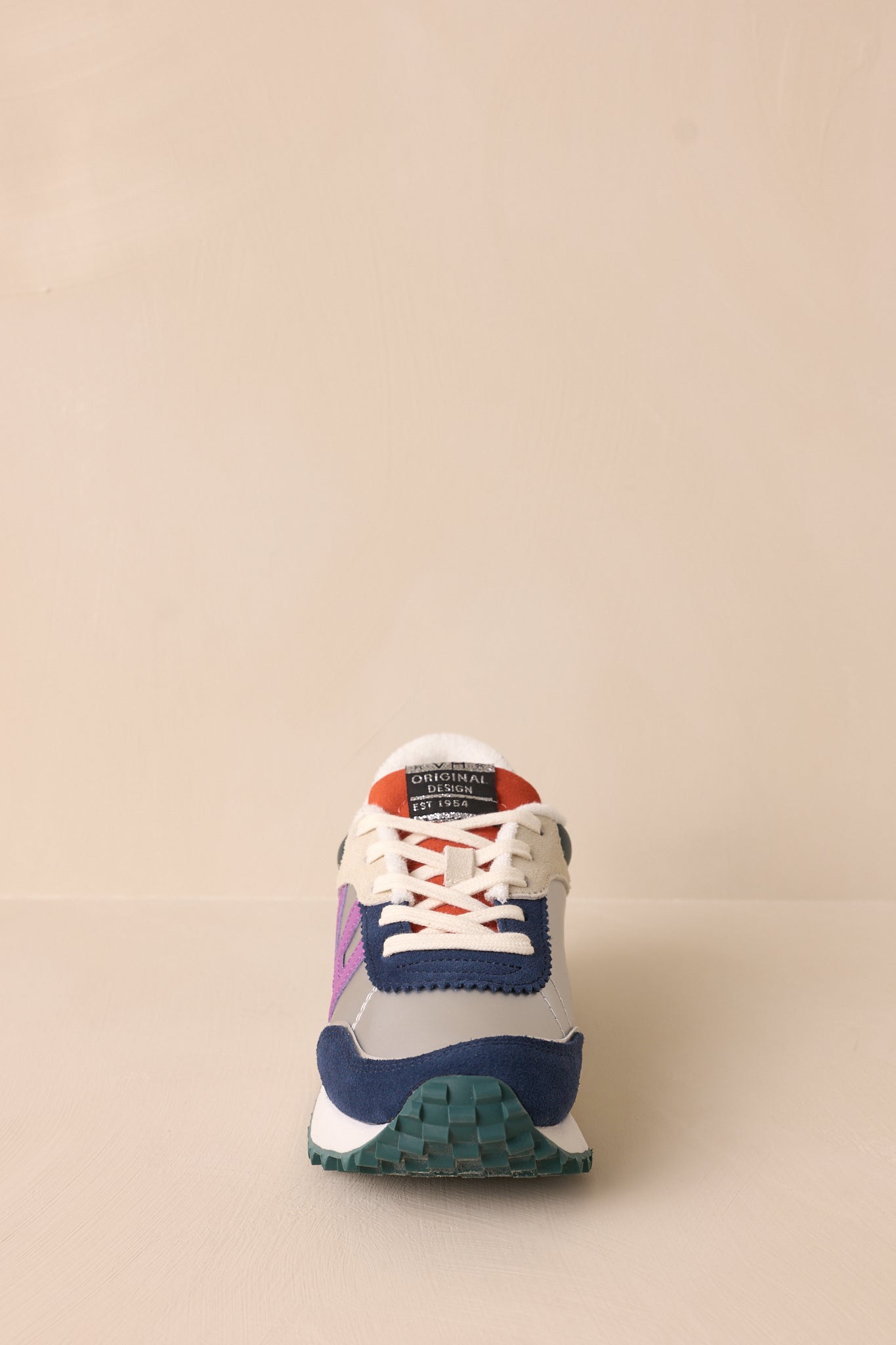 Front view of these silver sneakers that feature a rounded toe, functional laces, subtle pops of purple, navy, orange and silver, a slight platform, and a heavily textured sole.