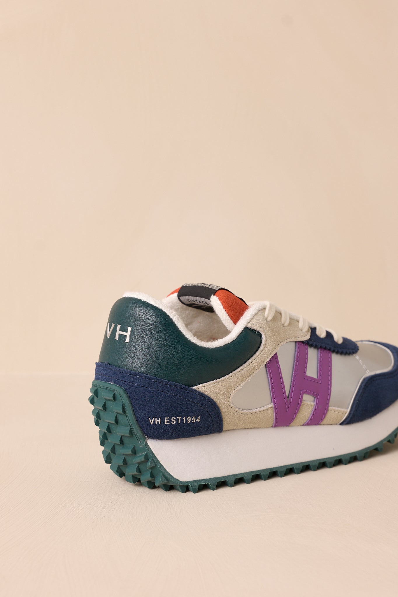 Back view of these silver sneakers that feature a rounded toe, functional laces, subtle pops of purple, navy, orange and silver, a slight platform, and a heavily textured sole.