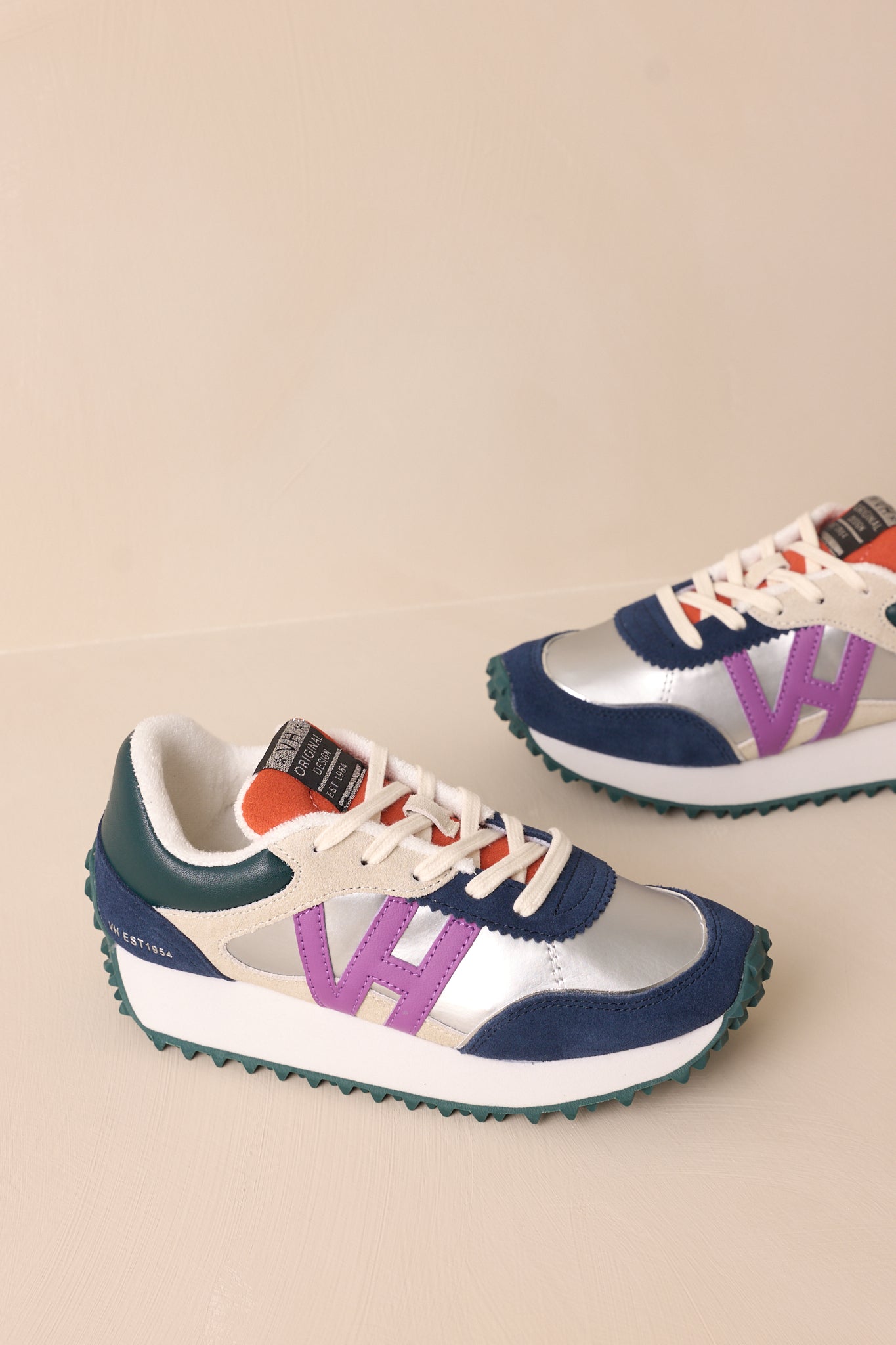 Over-head view of these silver sneakers that feature a rounded toe, functional laces, subtle pops of purple, navy, orange and silver, a slight platform, and a heavily textured sole.