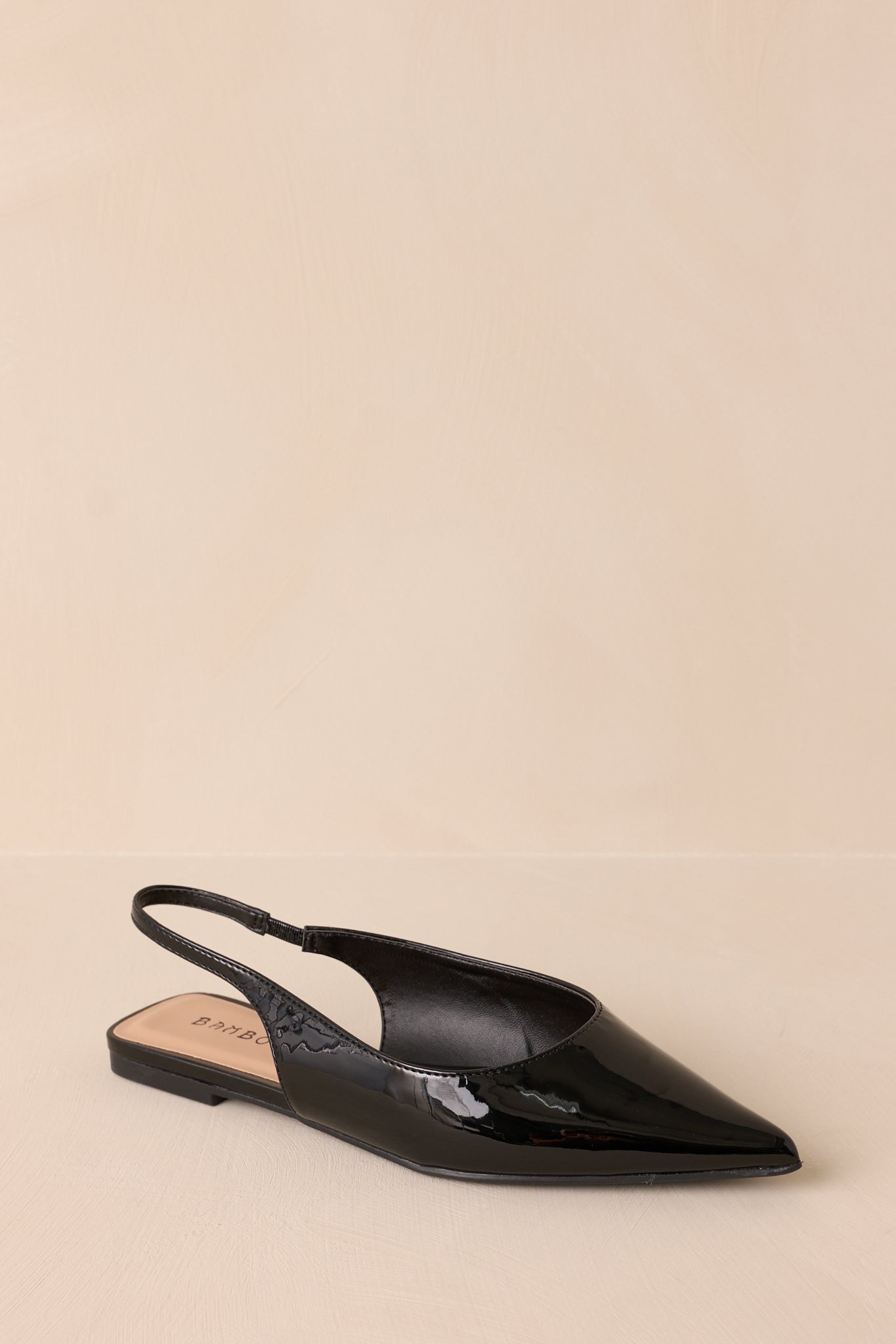 Focused view of the flats’ pointed toe, highlighting the glossy black patent finish and clean lines.