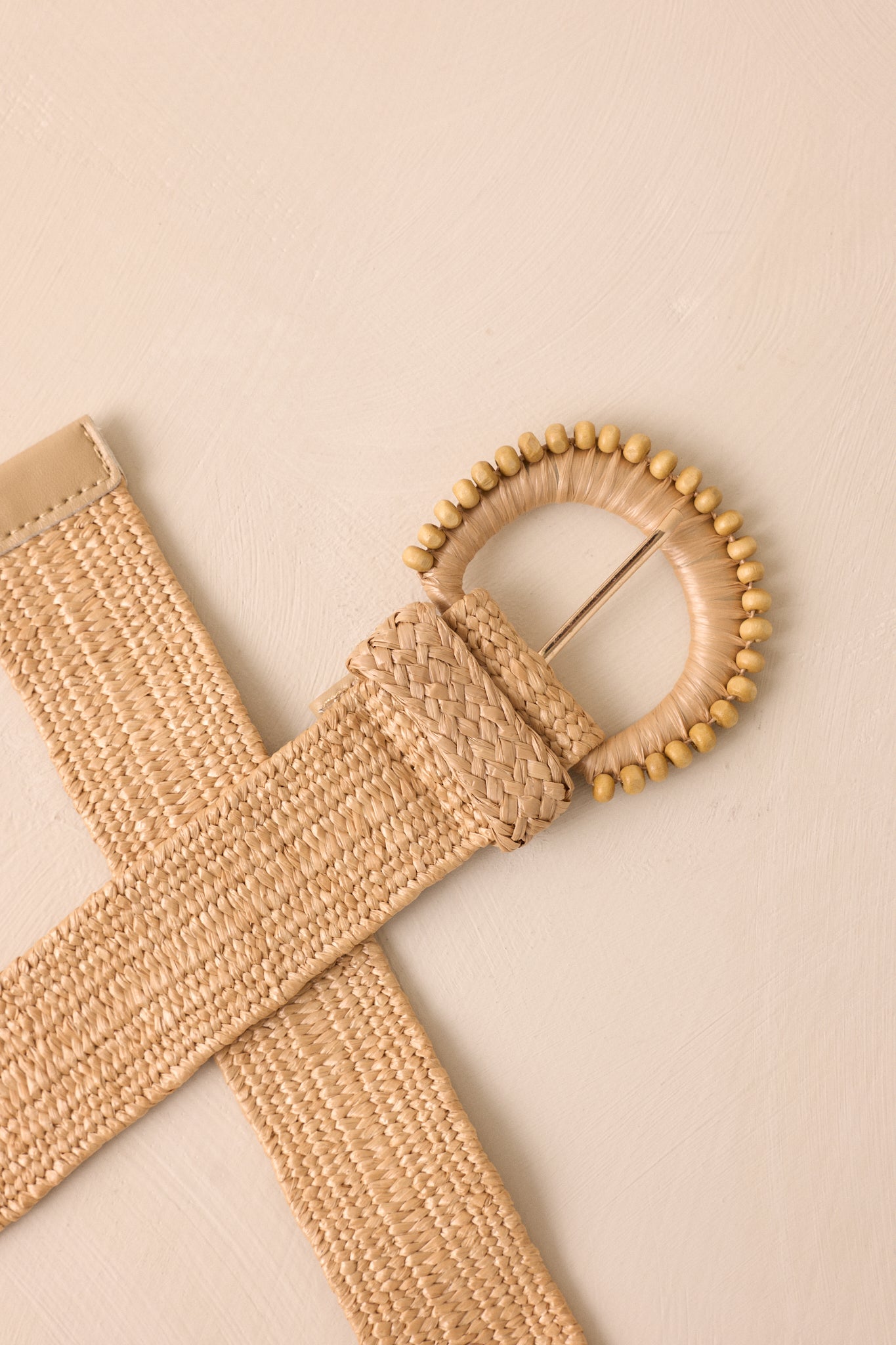 An up-close detail shot of the rounded buckle on the khaki belt, highlighting the gold hardware and beaded accents.