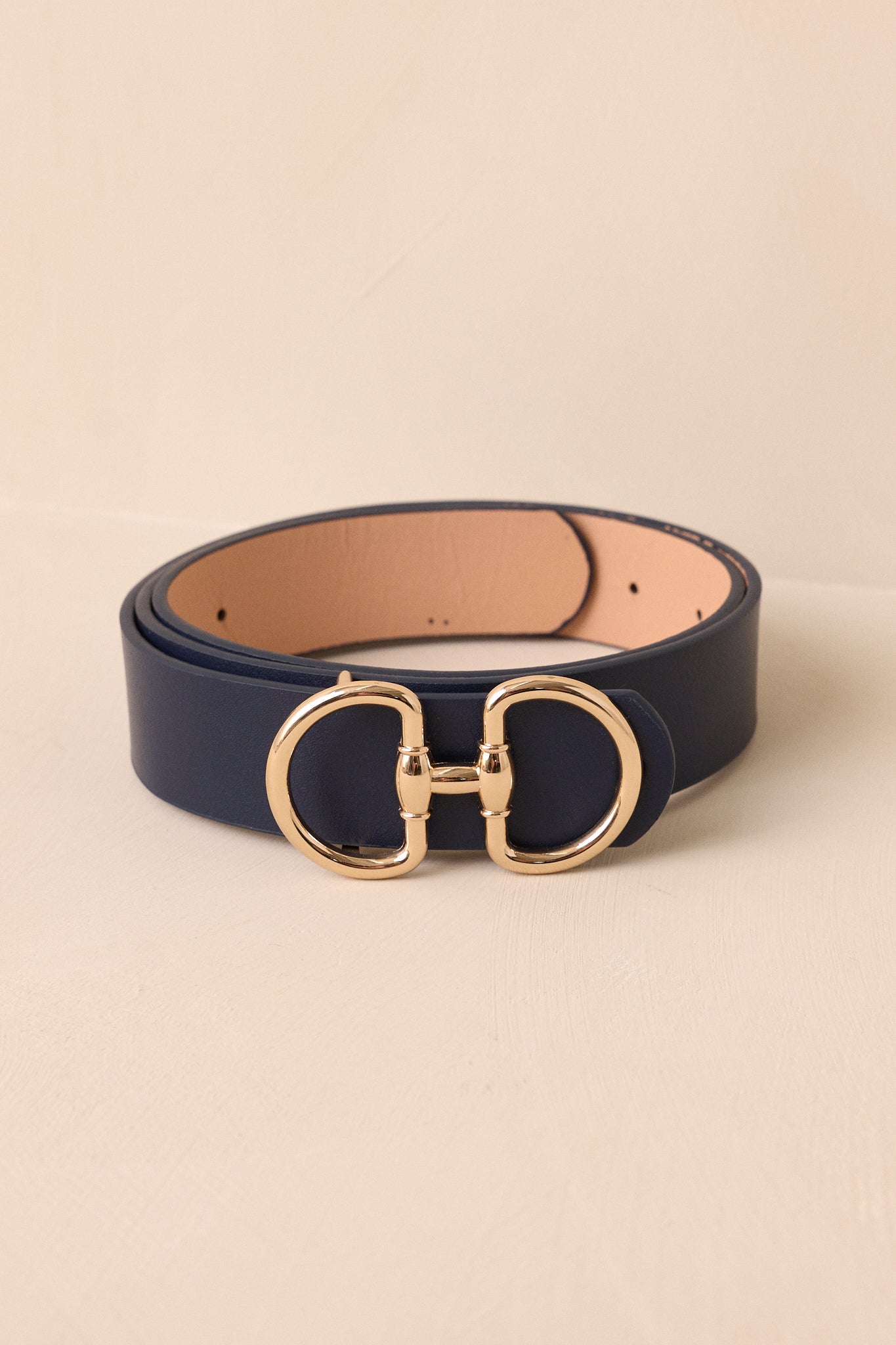 This navy belt features a link buckle closure with two prongs, a soft exterior, and gold hardware.