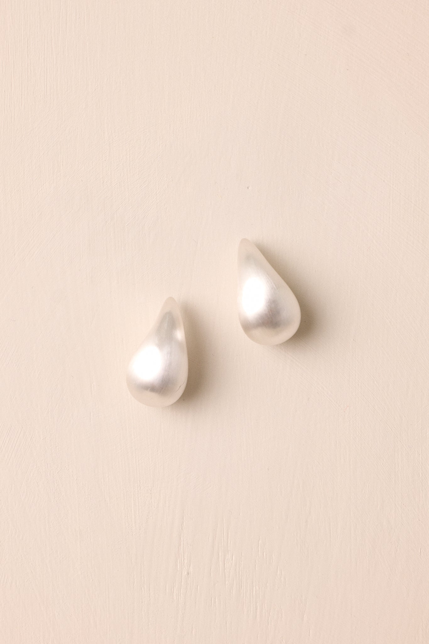 Detailed close-up of the teardrop earring, emphasizing the secure post backing and the subtle matte silver finish.