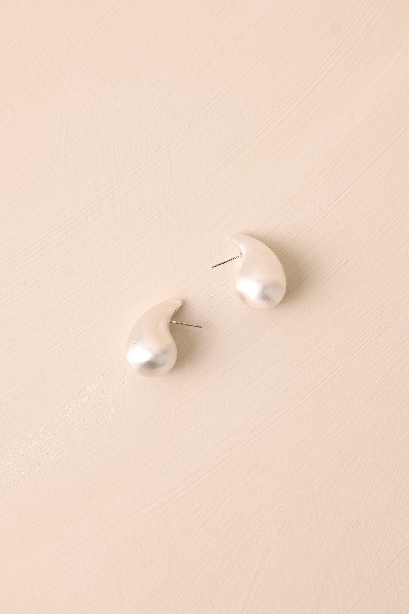 Side angle close-up of the earring, highlighting the matte silver texture and the elegant, elongated teardrop shape.