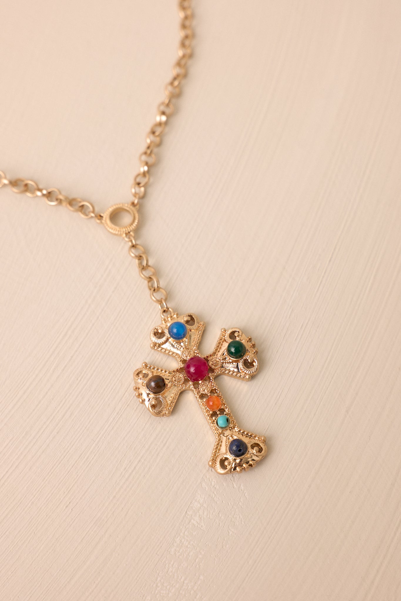 Zoomed-in view of the cross-shaped pendant adorned with multi-color faux pearls, emphasizing the texture of the pendant and the luminous quality of the pearls.