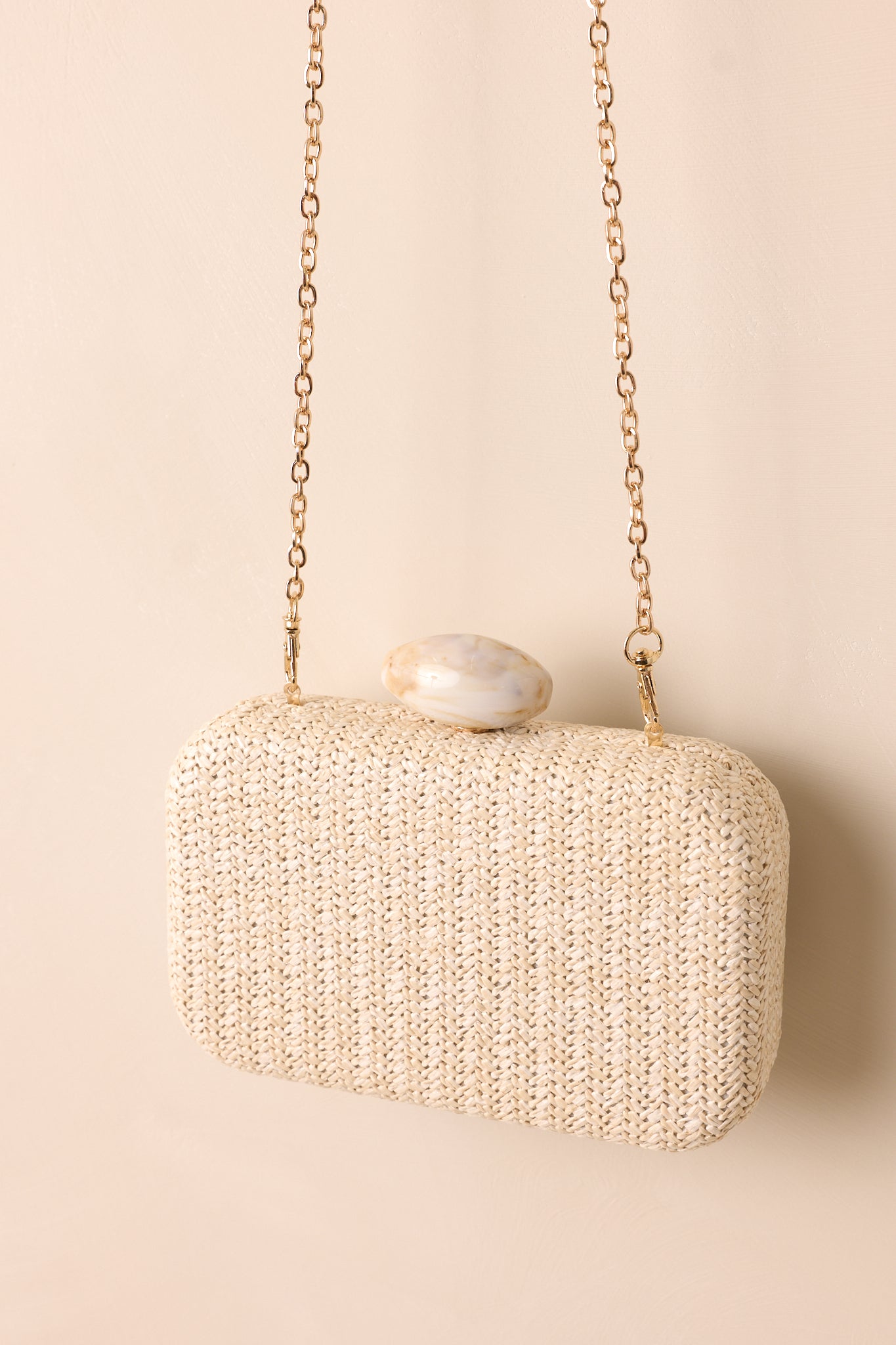 Side profile of a clutch against a beige backdrop, emphasizing its slim, streamlined silhouette and sophisticated closure