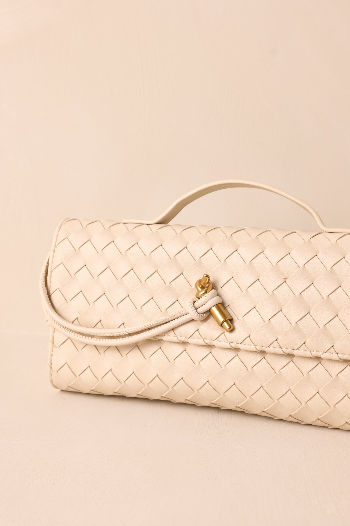 A close-up of the handbag’s top handle and gold hardware, emphasizing its sleek and elegant design.