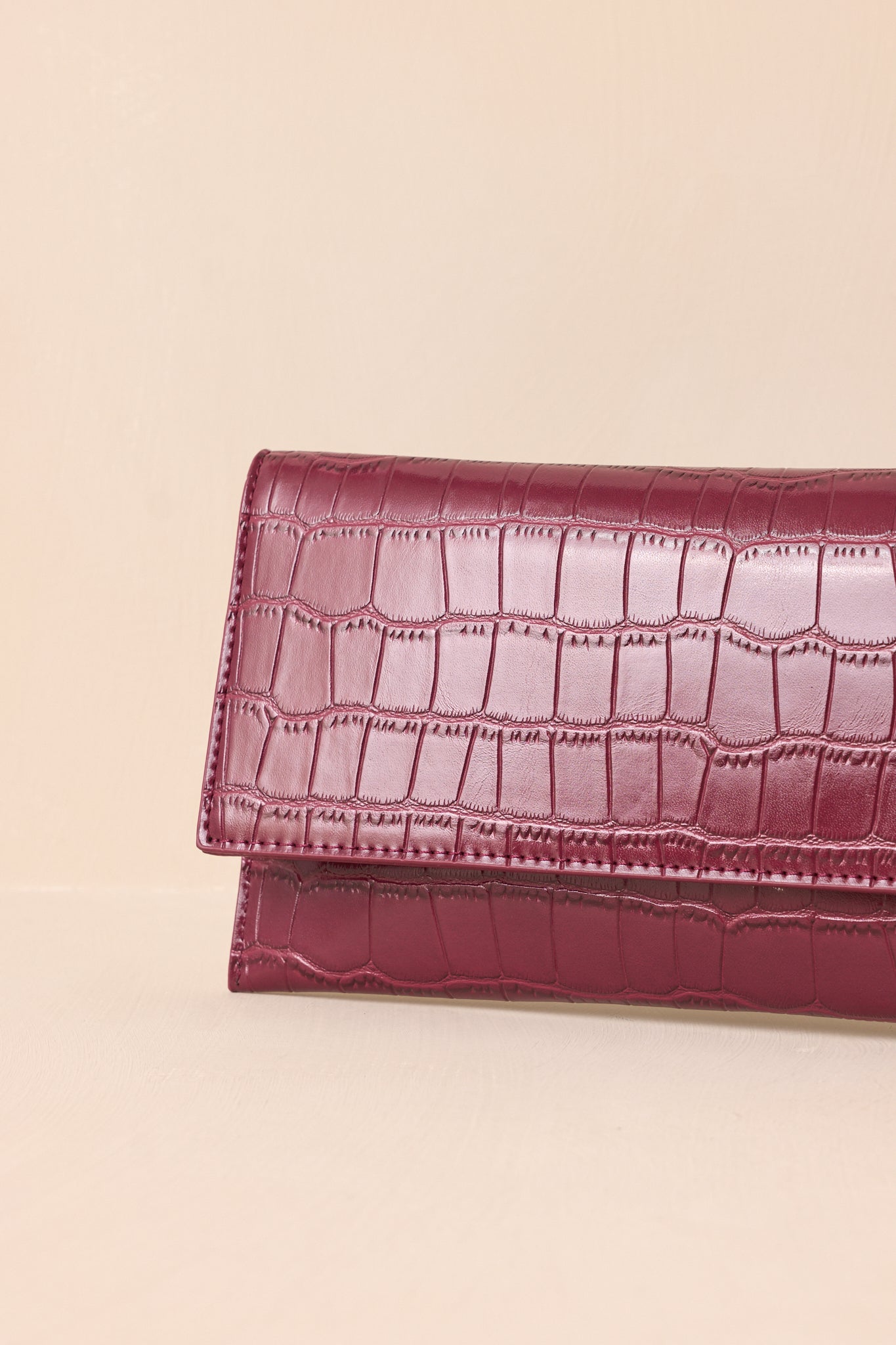 A close-up detail shot of the wine clutch’s refined stitching of the faux crocodile material.