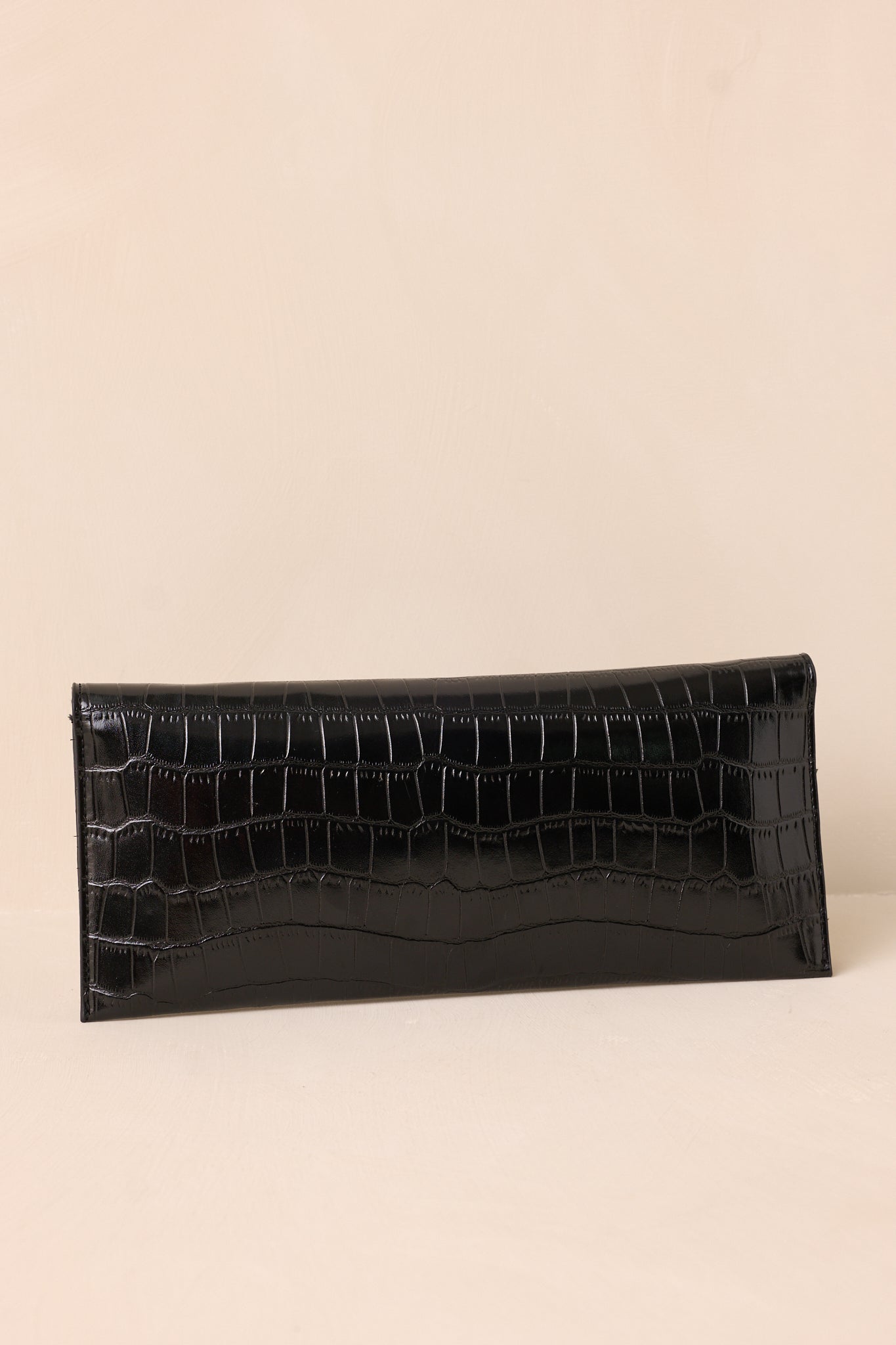 The back of the black clutch, showing the continuous faux crocodile pattern with a smooth, clean design.