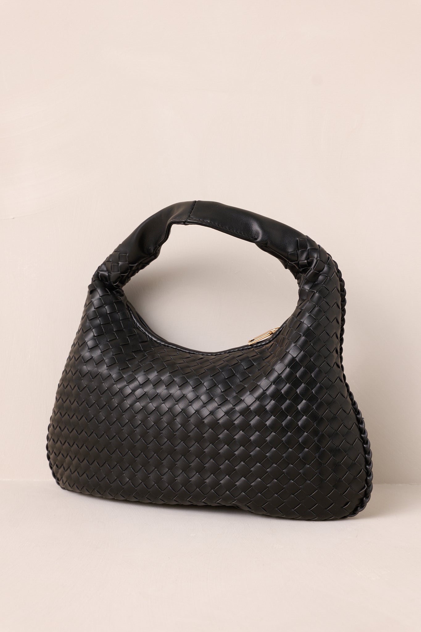 Stylish black handbag made of tightly woven material, featuring a solid faux leather handle and a chic gold zipper closure.