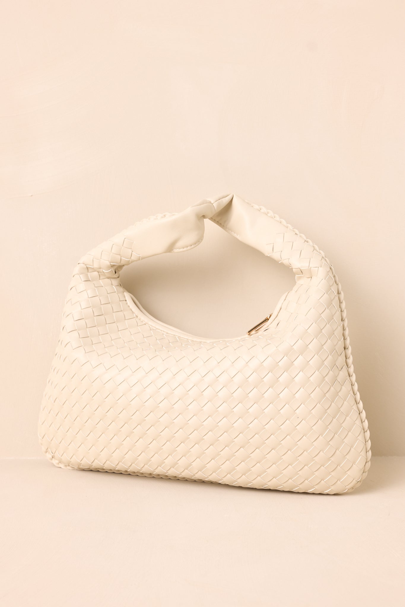 Another angle of the Oatmilk handbag with a woven texture, solid faux leather handle, and gold zipper. The bag stands upright showcasing its spacious design.