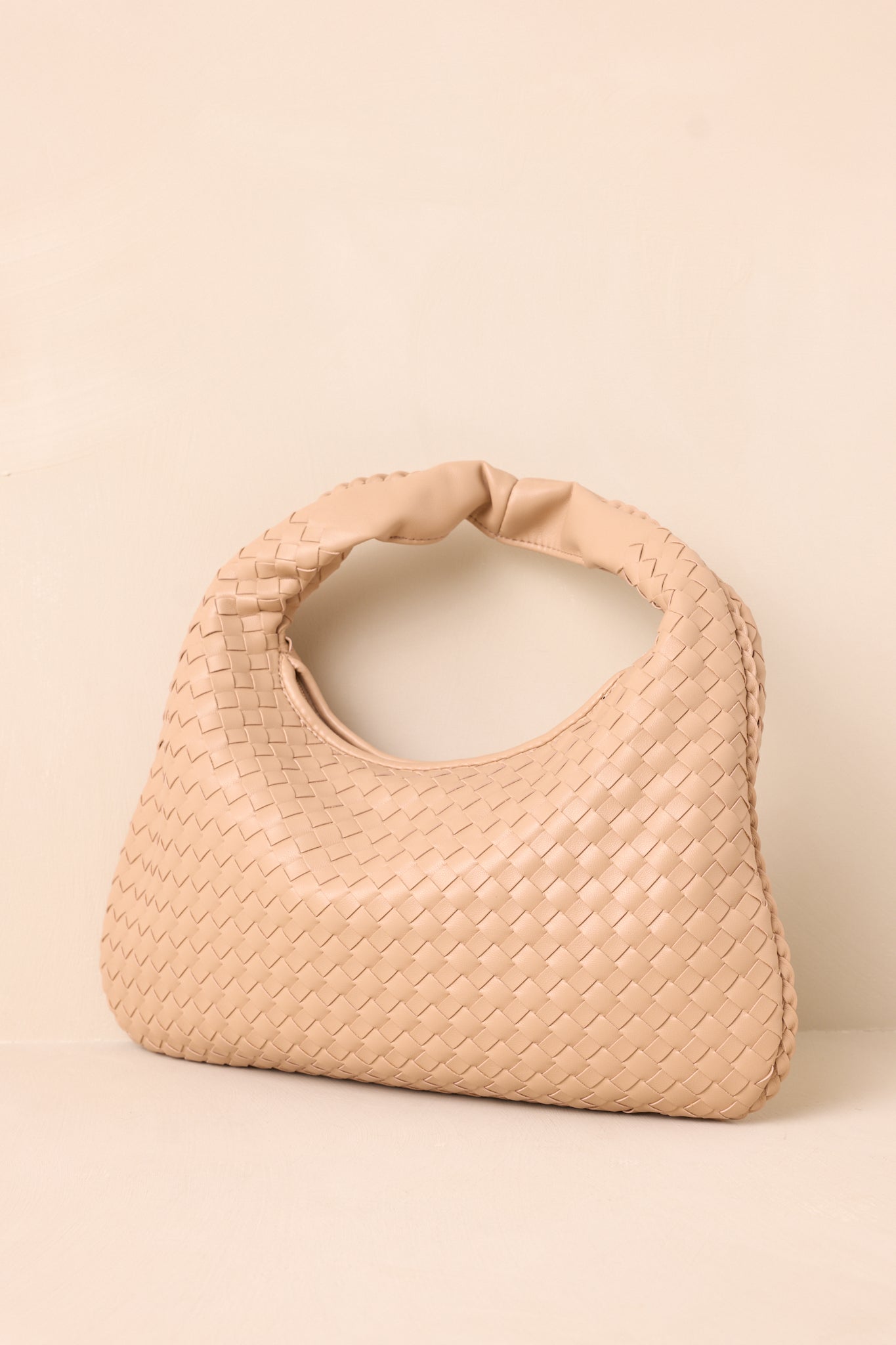 Another angle of the tan handbag with a woven texture, solid faux leather handle, and gold zipper. The bag stands upright showcasing its spacious design.