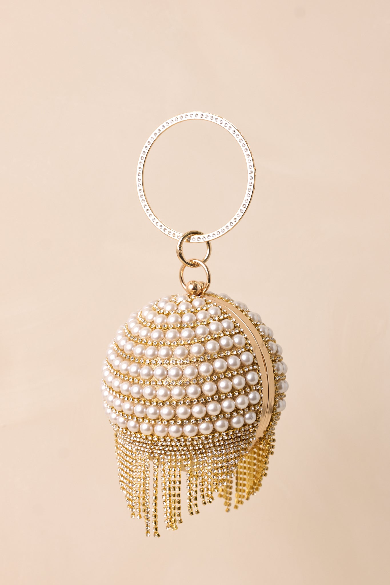 The clutch viewed from a closer angle, emphasizing the circular body and intricate rows of ivory faux pearls and diamonds.