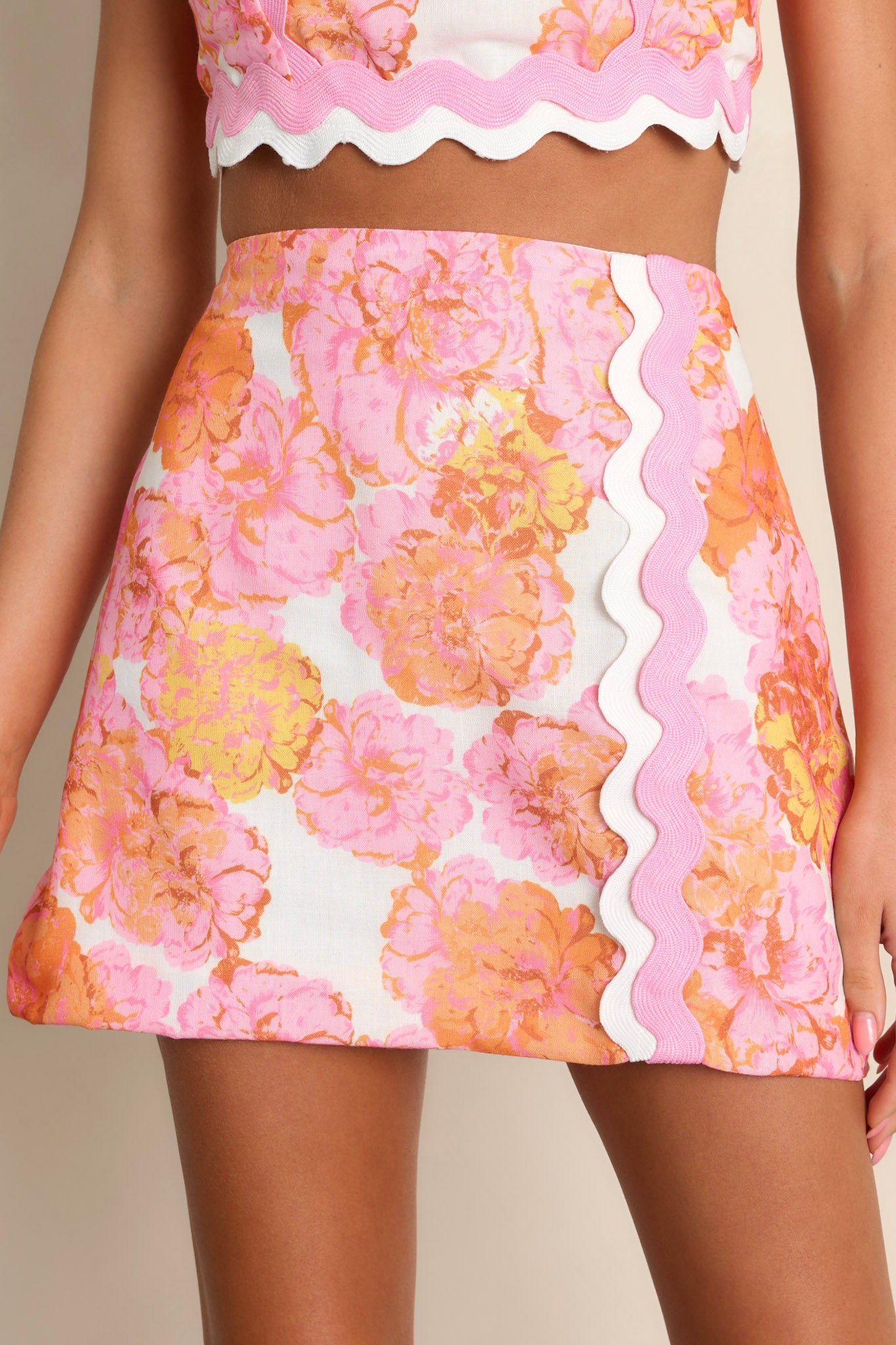 Close-up of the light pink floral mini skirt showing the high waisted design, functional zipper, and ricrac detailing.