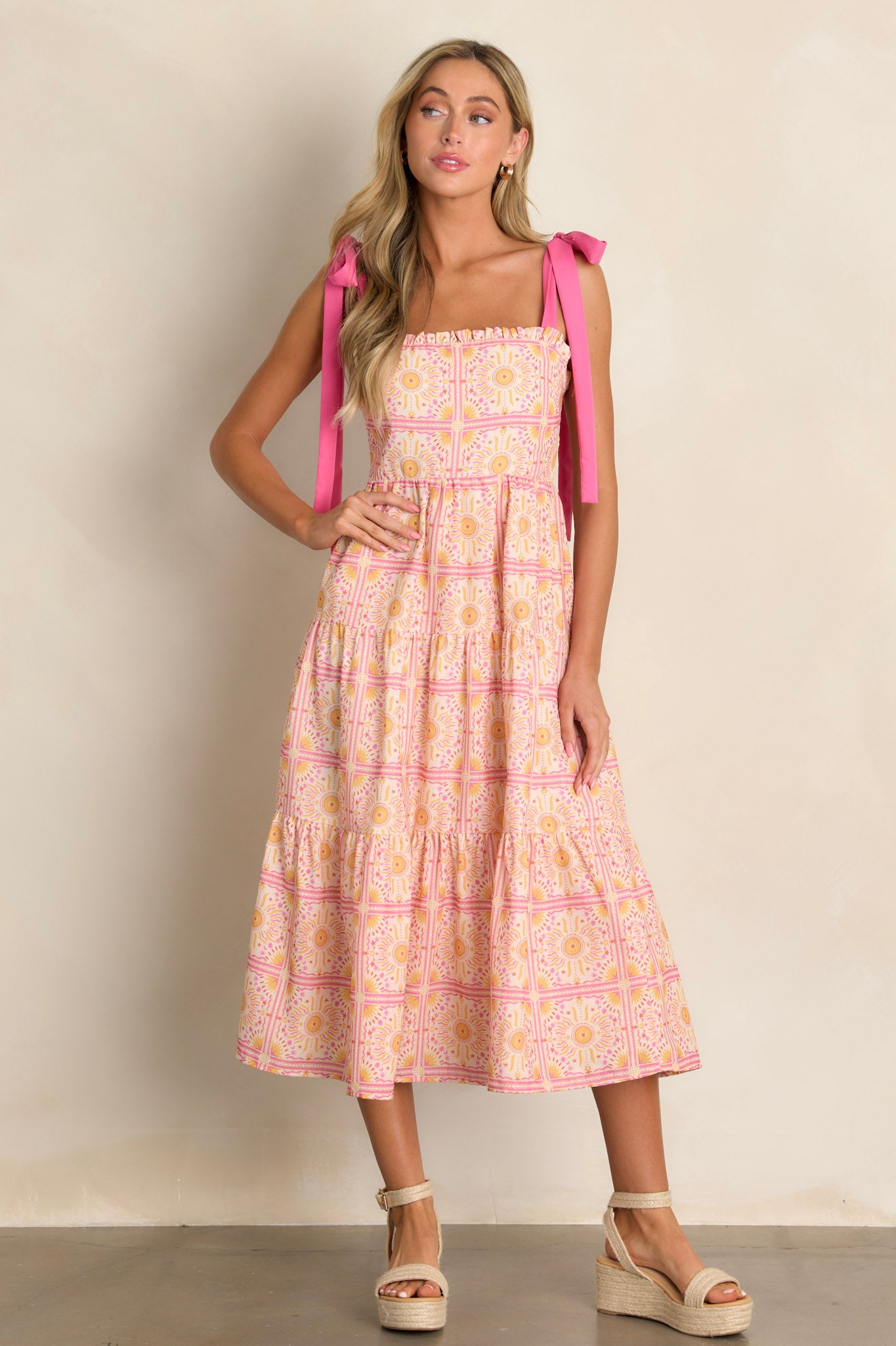 This pink multi midi dress features a ruffled square neckline, a fully smocked back, a tiered design, a unique print, and a flowing silhouette.