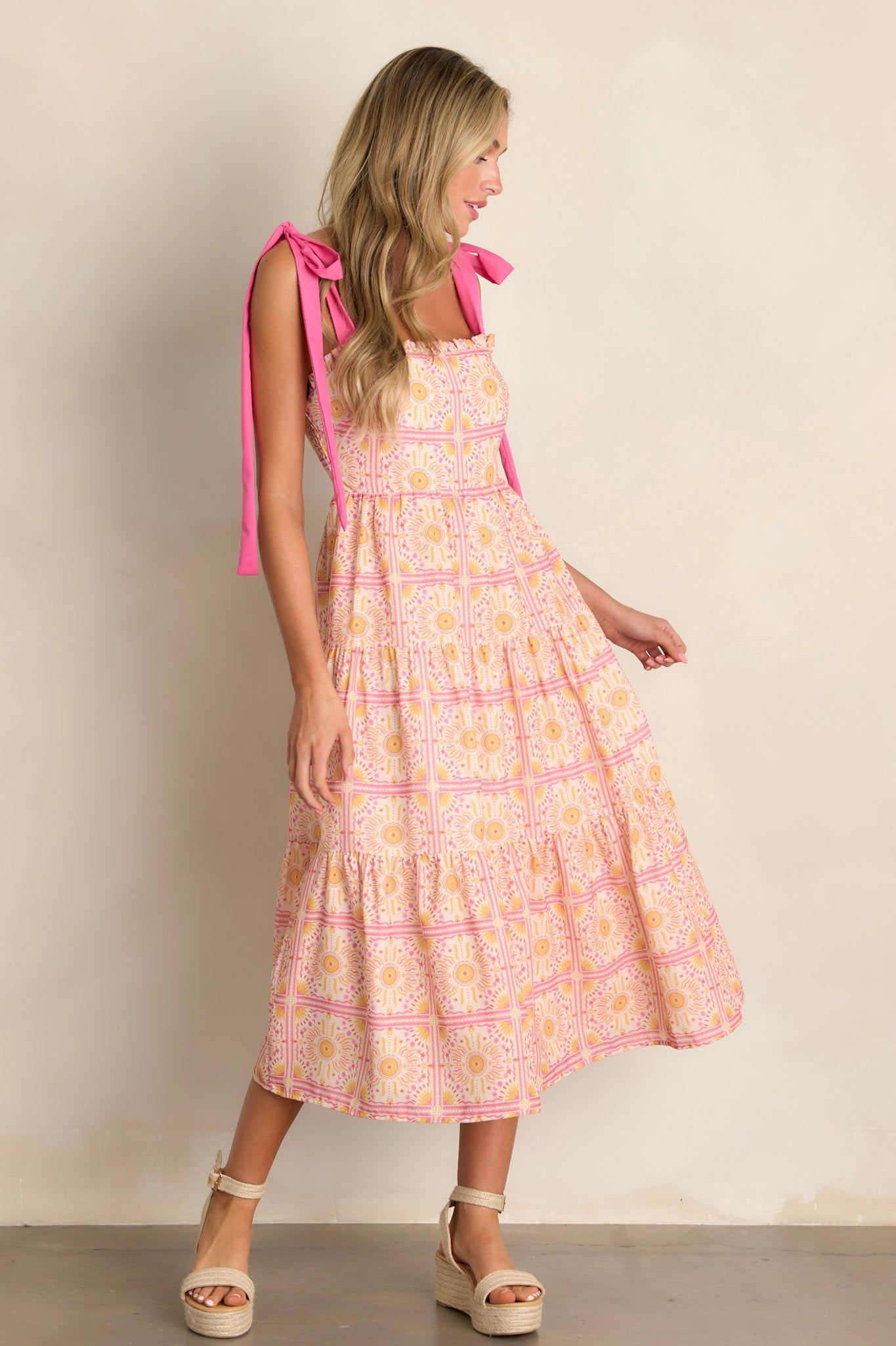 Side view of a pink multi midi dress showcasing the ruffled square neckline, tiered design, unique print, and flowing silhouette.