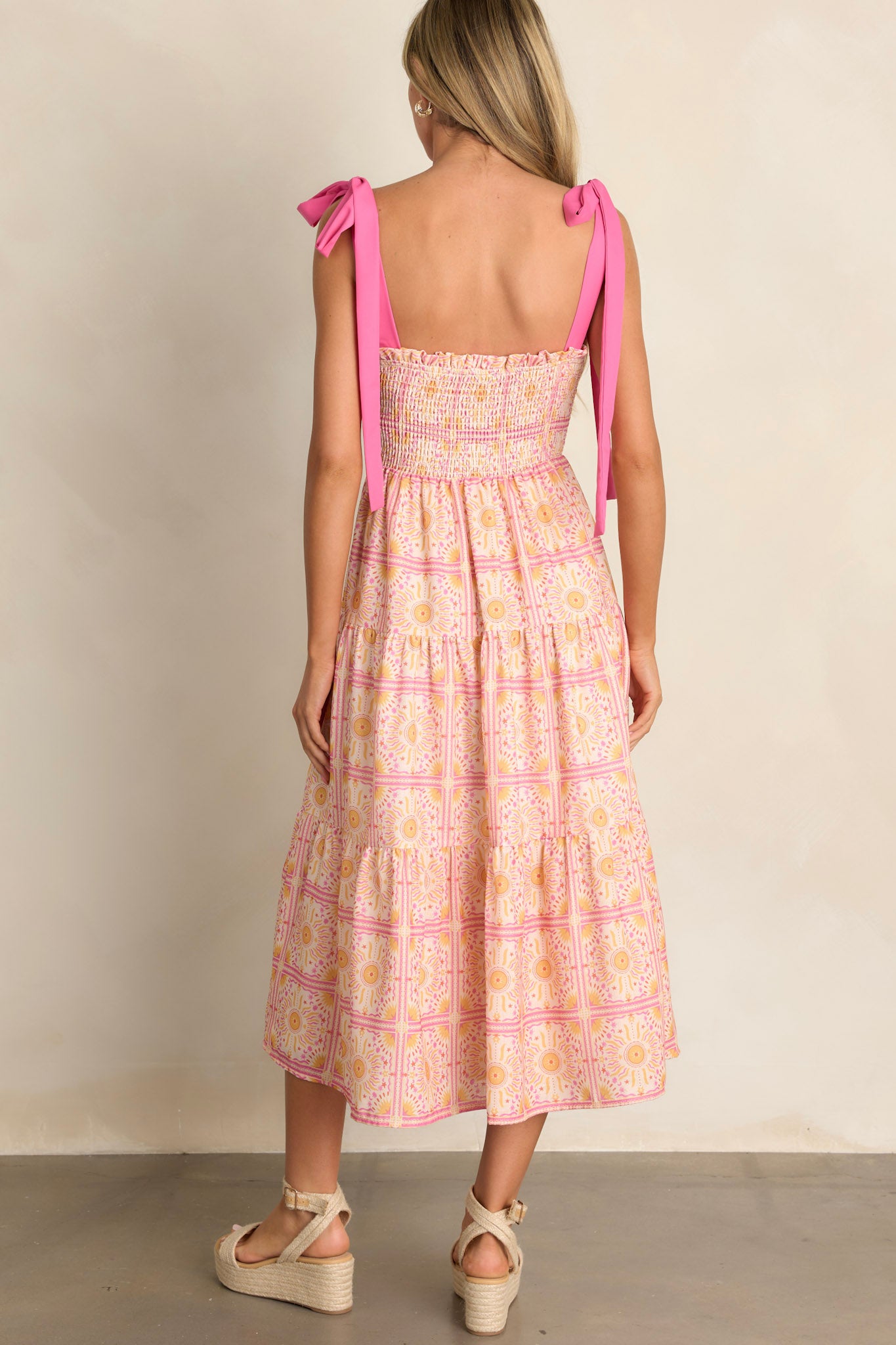 Back view of a pink multi midi dress highlighting the fully smocked back, tiered design, and overall fit.