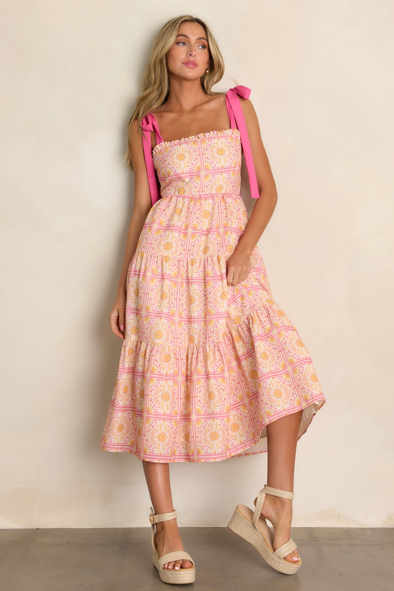 Full length view of a pink multi midi dress with a ruffled square neckline, a fully smocked back, a tiered design, a unique print, and a flowing silhouette