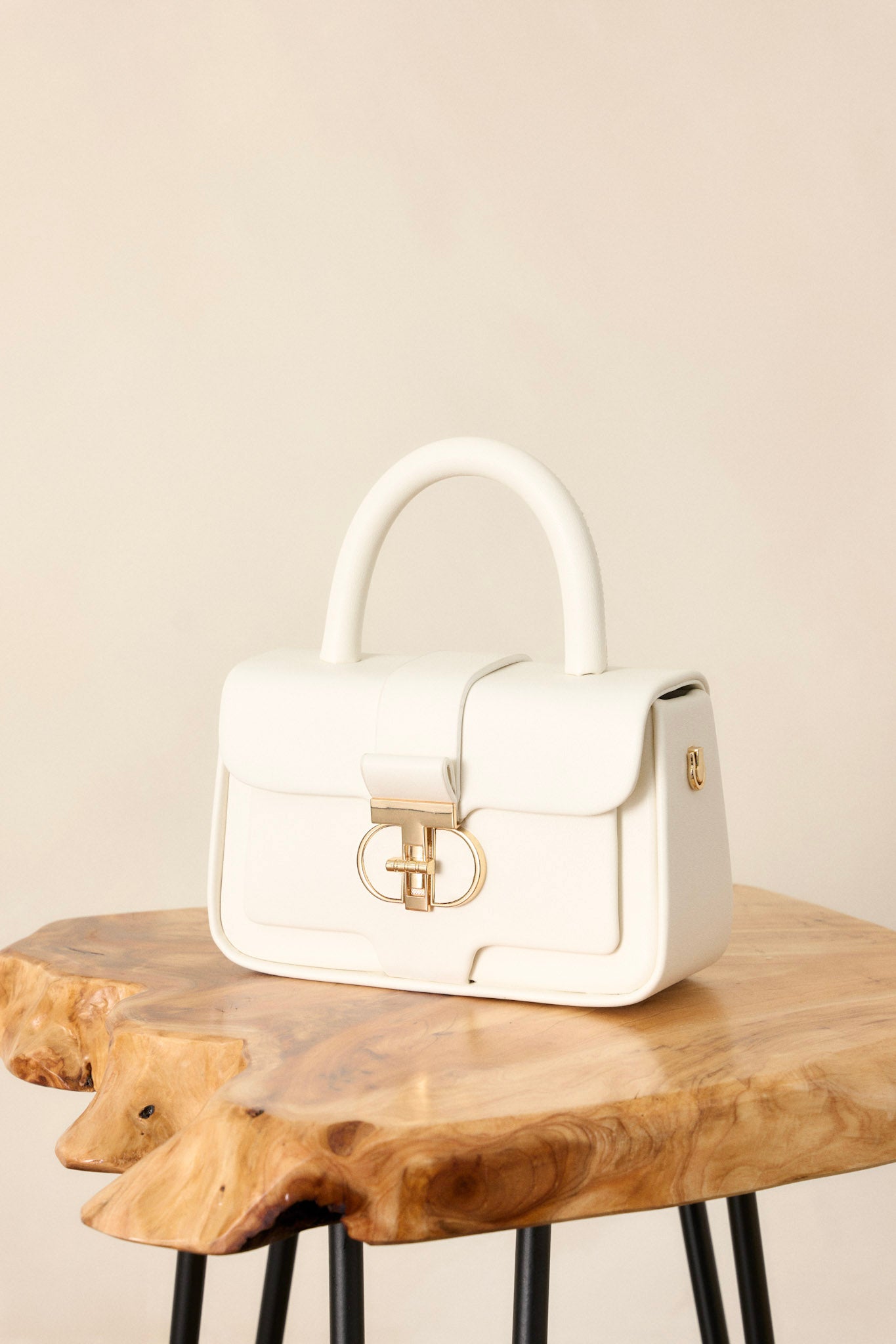 Close up view of this white handbag featuring gold hardware, an inside pocket, an included matching wallet, optional crossbody strap, and a top handle design.