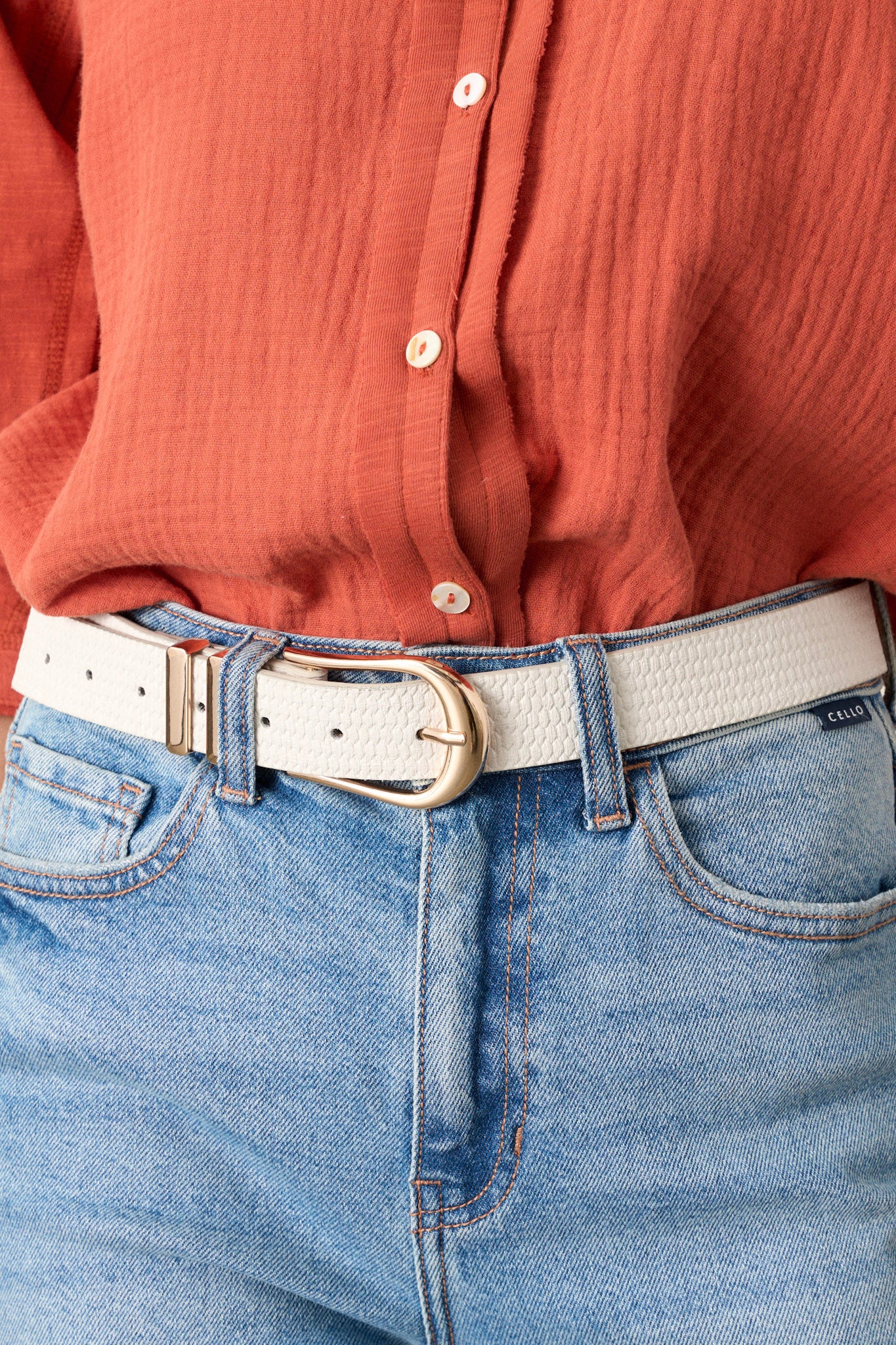 This ivory woven belt features gold hardware buckle, a tan inside, a woven texture and two gold belt loops.