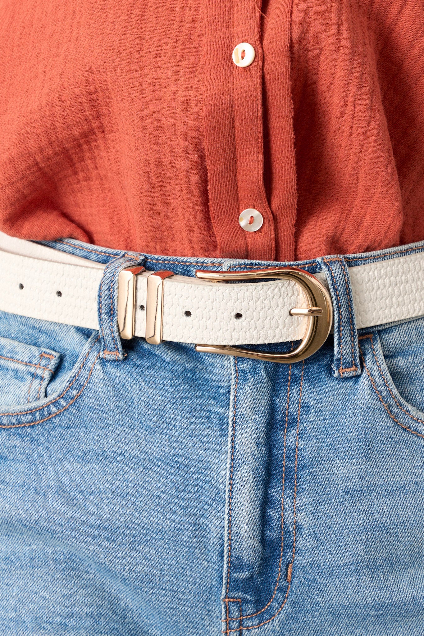 Close-up of the ivory woven belt focusing on the gold hardware buckle, the woven texture, and the tan interior.