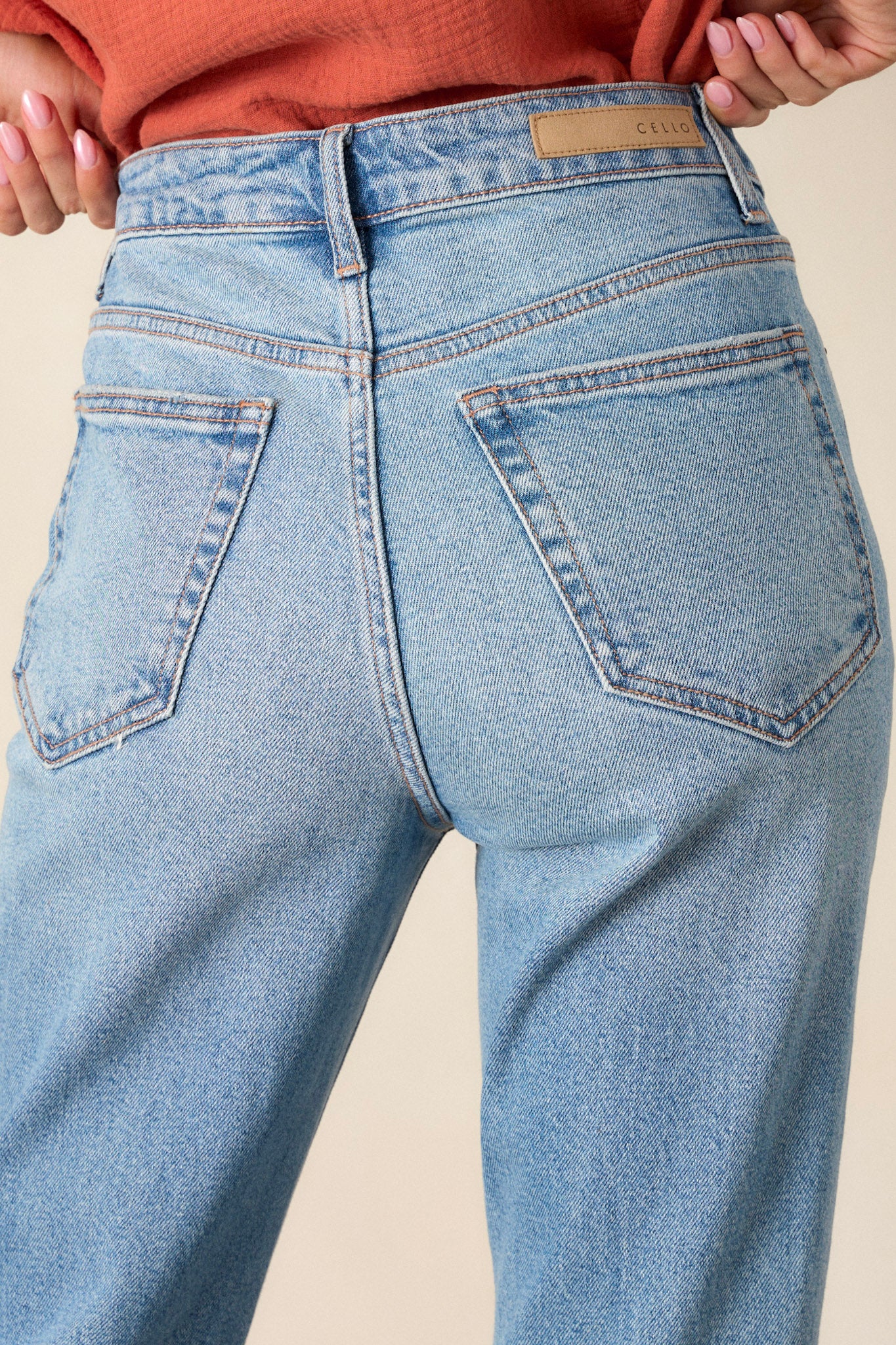 Close up back view of these medium wash straight leg jeans featuring 5-pocket detailing and a standard zipper and button closure.