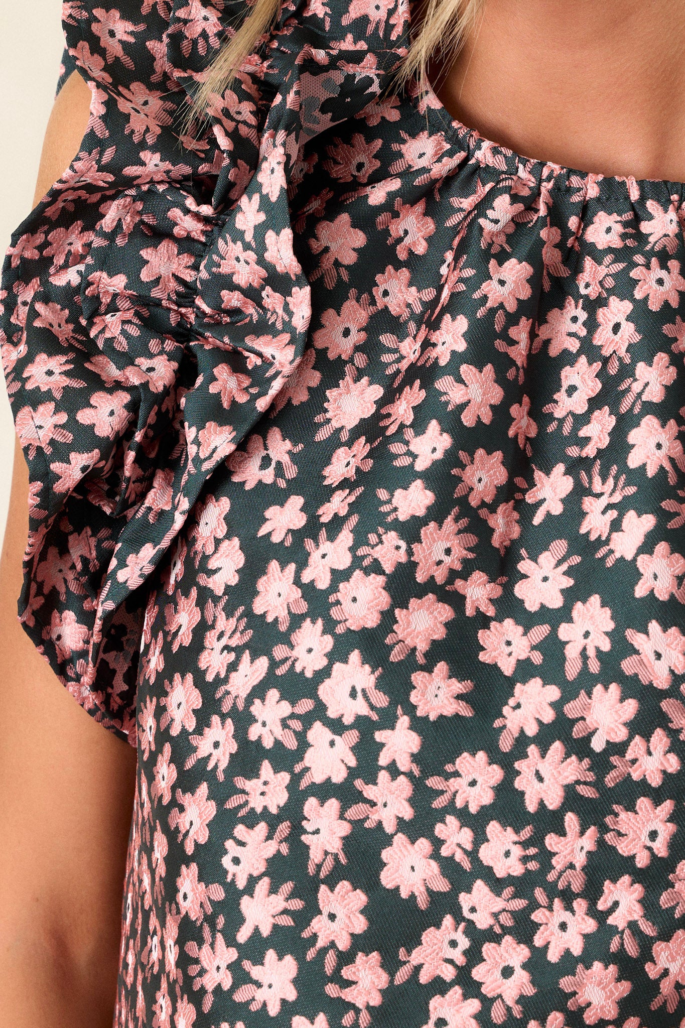 Close-up of the hunter green floral top focusing on the intricate floral embroidery and the ruffled sleeveless design near the neckline.