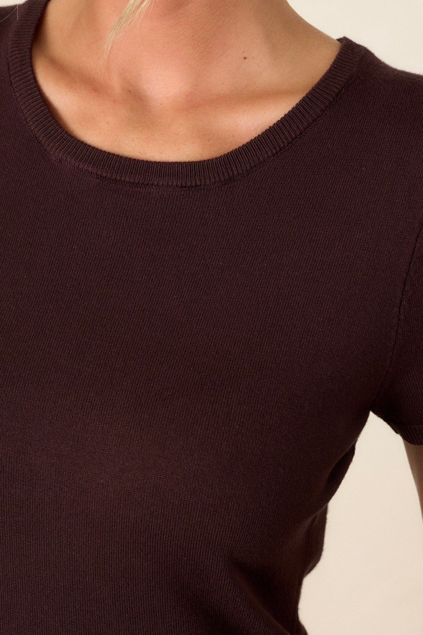 Close-up of the dark brown sweater top focusing on the rounded neckline, soft sweater fabric, and ribbed hem.