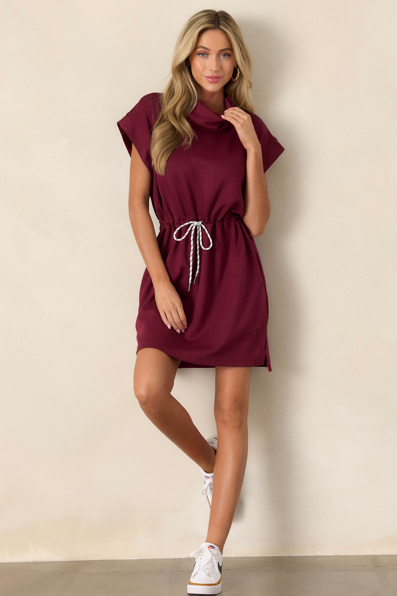 Burgundy mini dress with short cap sleeves, drawstring waist, cowl turtleneck, and functional pockets.