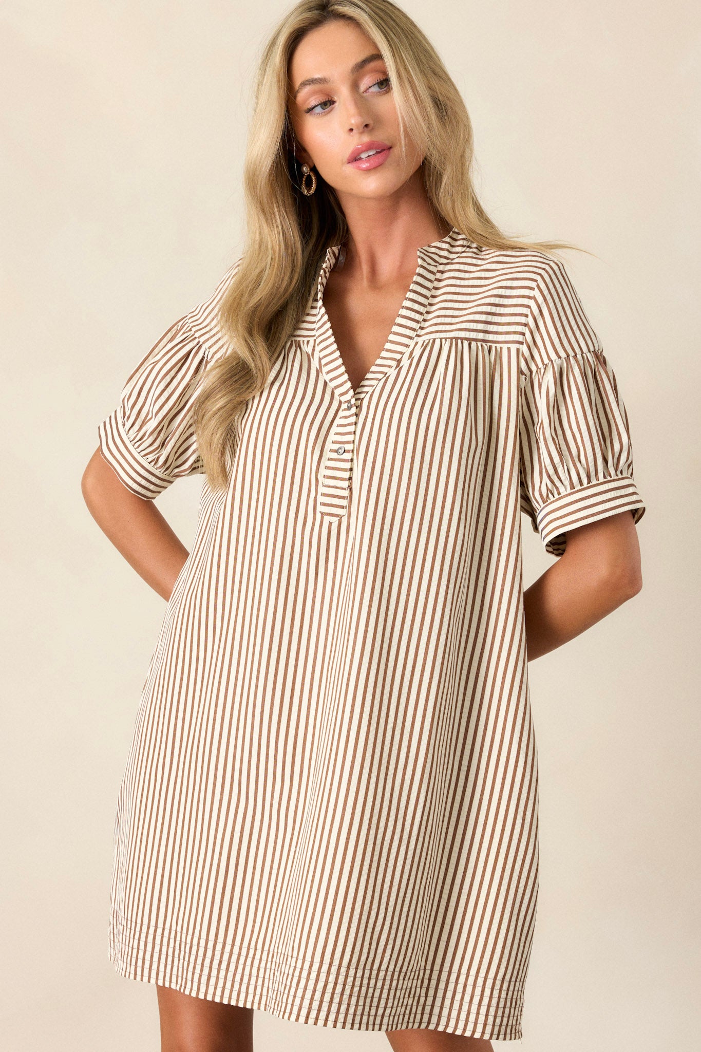 This brown stripe dress features a v-neckline, a button up bust, a relaxed fit, a vertical brown and white stripe design and short sleeves.